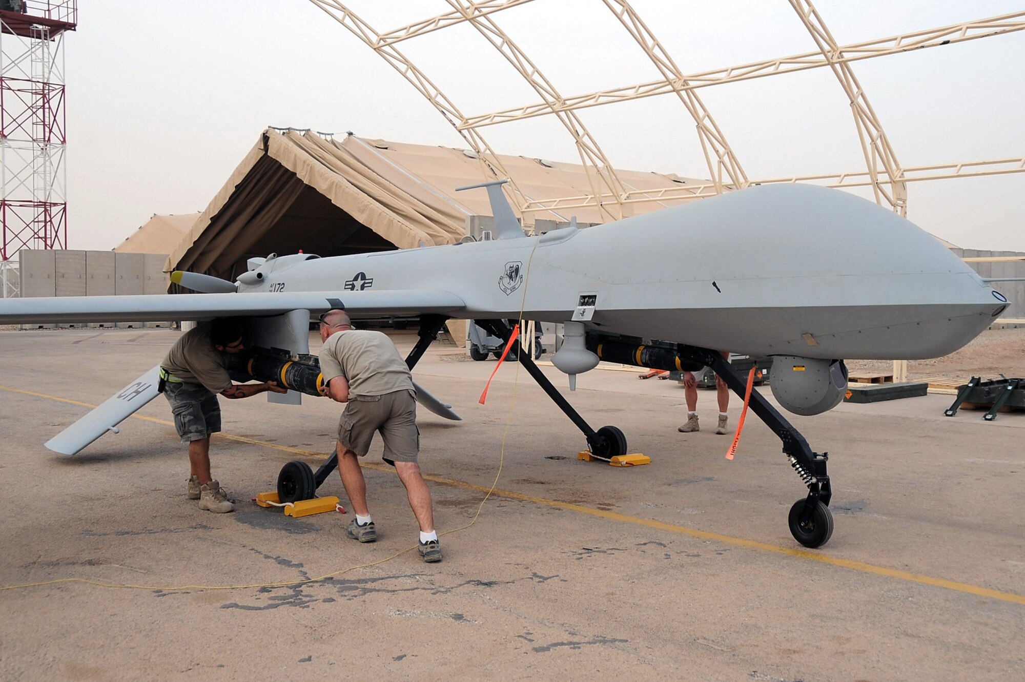 Shilo Thompson and Brandon Walker load a Hellfire missile on an MQ-1B Predator unmanned aircraft July 9 at Ali Base, Iraq. Through the use of advanced capabilities, focused doctrine and detailed training, the Predator provides integrated and synchronized close air combat operations, to include intelligence, surveillance and reconnaissance. The two aircraft mechanics are with the 361st Expeditionary Reconnaissance Squadron.  (U.S. Air Force photo/Tech. Sgt. Sabrina Johnson) 