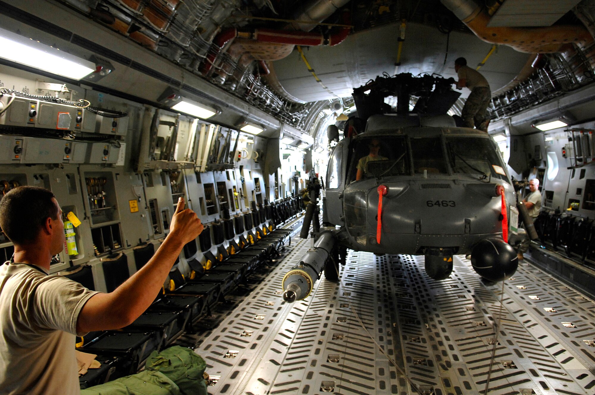 Tech. Sgt. Joseph Herrera gives a thumbs up to loadmasters during an upload of an HH-60 Pave Hawk into a C-17 Globemaster III July 12 at Joint Base Balad, Iraq. The helicopter is configured in a folded position that allows it to be loaded with enough clearance all around. Sergeant Herrera is a 64th Expeditionary Helicopter Maintenance Unit crew chief deployed from Davis-Monthan Air Force Base, Ariz. (U.S. Air Force photo/Senior Airman Julianne Showalter) 