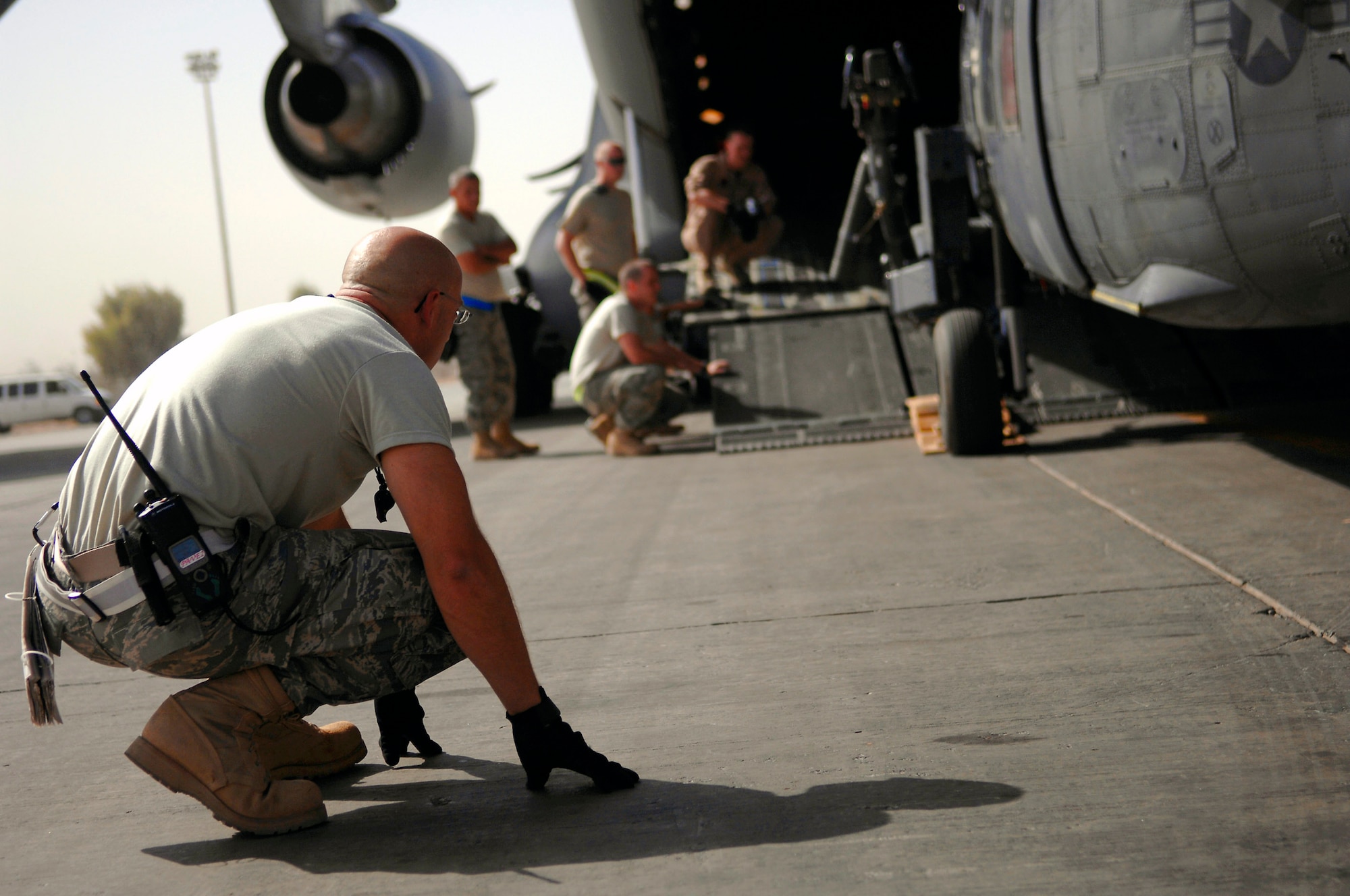 Tech. Sgt. Jason Lauer watches the underbelly on an HH-60 Pave Hawk while it's loaded onto a C-17 Globemaster III July 12 at Joint Base Balad, Iraq. A winch system on the C-17 is hooked to the helicopter and slowly drags it into the ramp. Sergeant Lauer is a 64th Expeditionary Helicopter Maintenance Unit crew chief deployed from Davis-Monthan Air Force Base, Ariz. (U.S. Air Force photo/Senior Airman Julianne Showalter) 