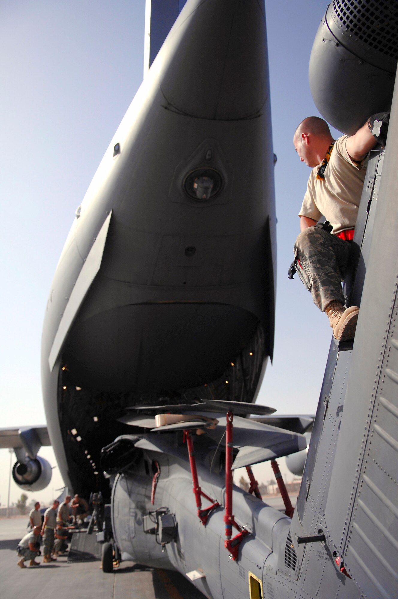 Staff Sgt. Joshua Sallander sits on the tail rotor of an HH-60 Pave Hawk while it's loaded onto a C-17 Globemaster III July 12 at Joint Base Balad, Iraq. Positioning several Airmen around and on the helicopter ensures it will not make contact with the aircraft and cause damage. The HH-60 is in a folded configuration to better fit into the C-17. Sergeant Sallander is a 64th Expeditionary Helicopter Maintenance Unit crew chief deployed from Davis-Monthan Air Force Base, Ariz. (U.S. Air Force photo/Senior Airman Julianne Showalter) 
