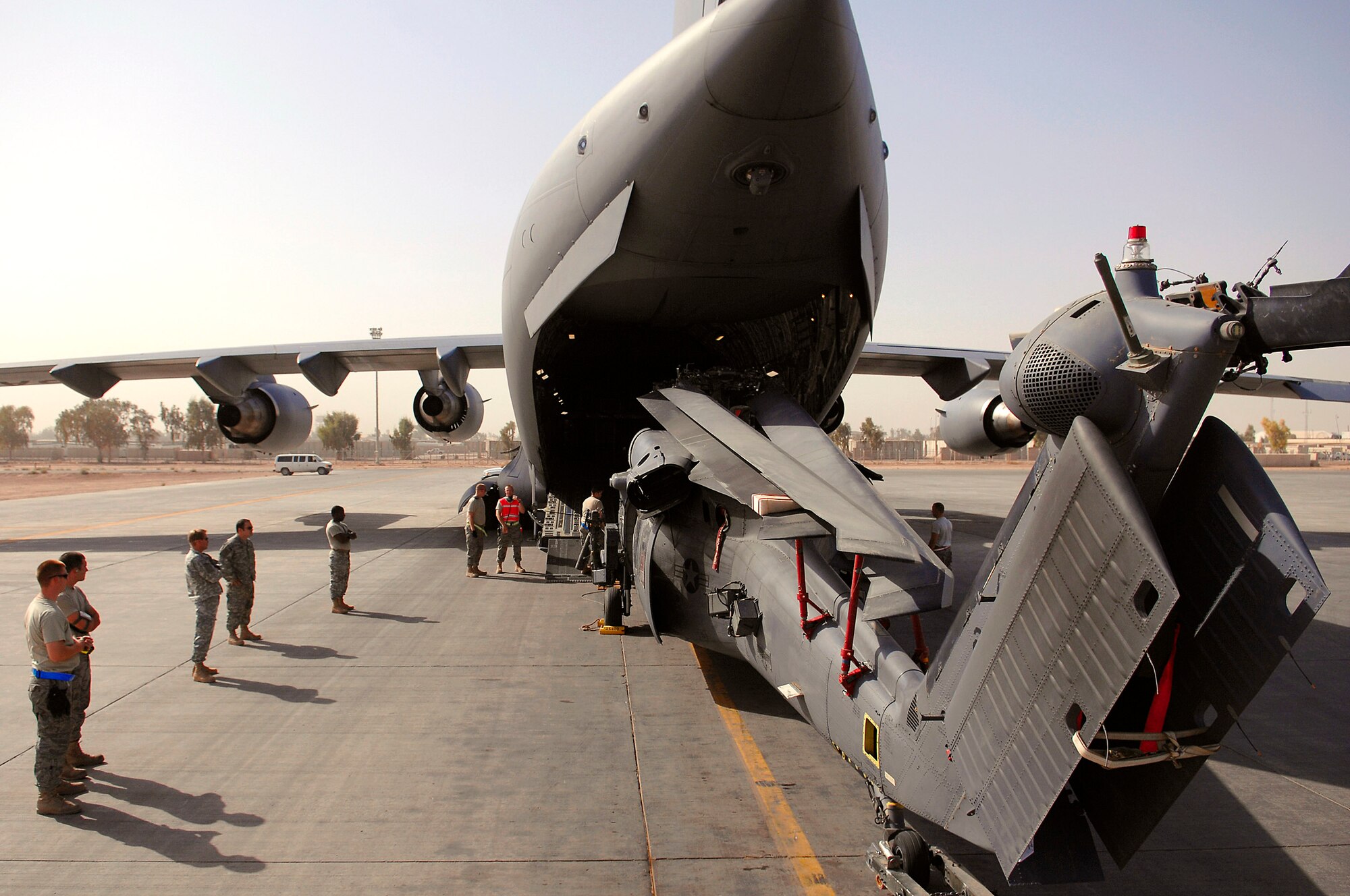 A team of Airmen assigned to the 64th Expeditionary Helicopter Maintenance Unit stand in position around an HH-60 Pave Hawk during upload into a C-17 Globemaster III July 12 at Joint Base Balad, Iraq. The Airmen position themselves 360 degrees around the helicopter to ensure it will not make contact with the aircraft. The Airmen are deployed from Davis-Monthan Air Force Base, Ariz. (U.S. Air Force photo/Senior Airman Julianne Showalter) 
