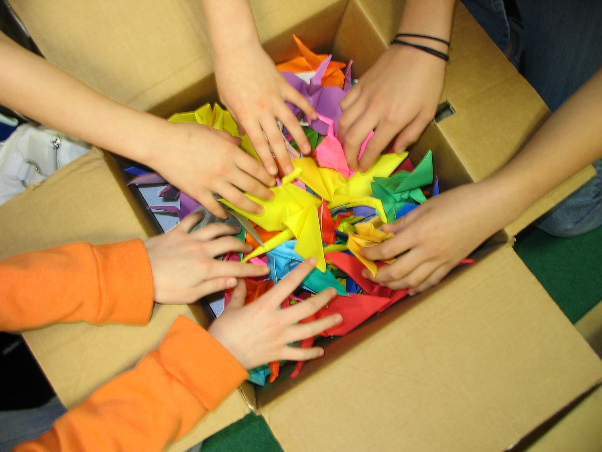 Three children from the Youth Center at Vance Air Force Base Okla., place cranes inside a box that will be delivered to the Oklahoma Memorial Foundation. The cranes are part of The Hope Box project, an attempt to teach about the effects of discrimination. (U.S. Air Force Photo by Stephen Fuller) 