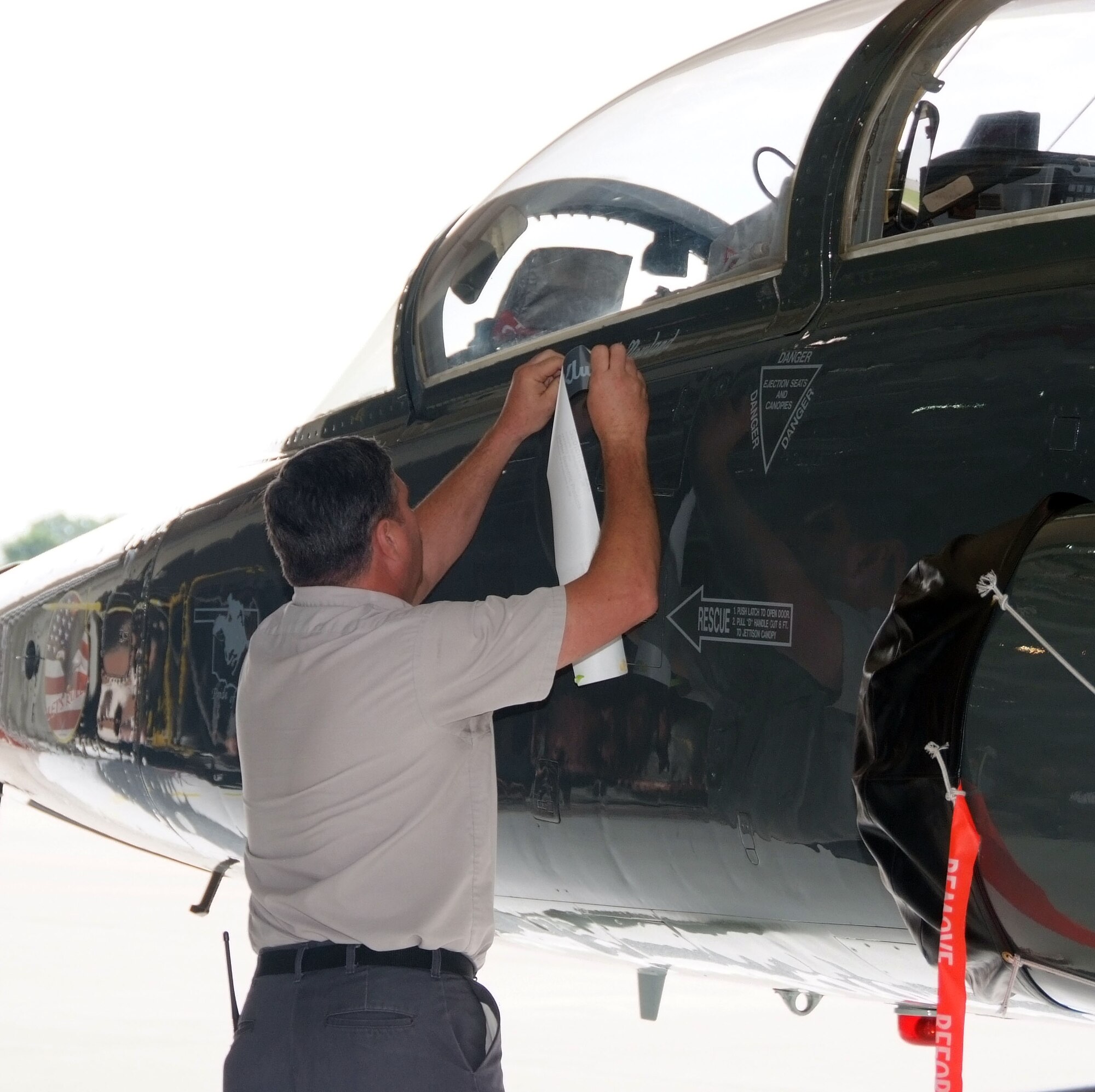 Aircraft mechanic David L. Reese removes the tape covering Col. Mark C. Nowland’s name on the wing flag ship, a T-38 Talon, during a change of command ceremony held July 11 at Vance AFB, Okla. (U.S. Air Force photo by Terry Wasson)