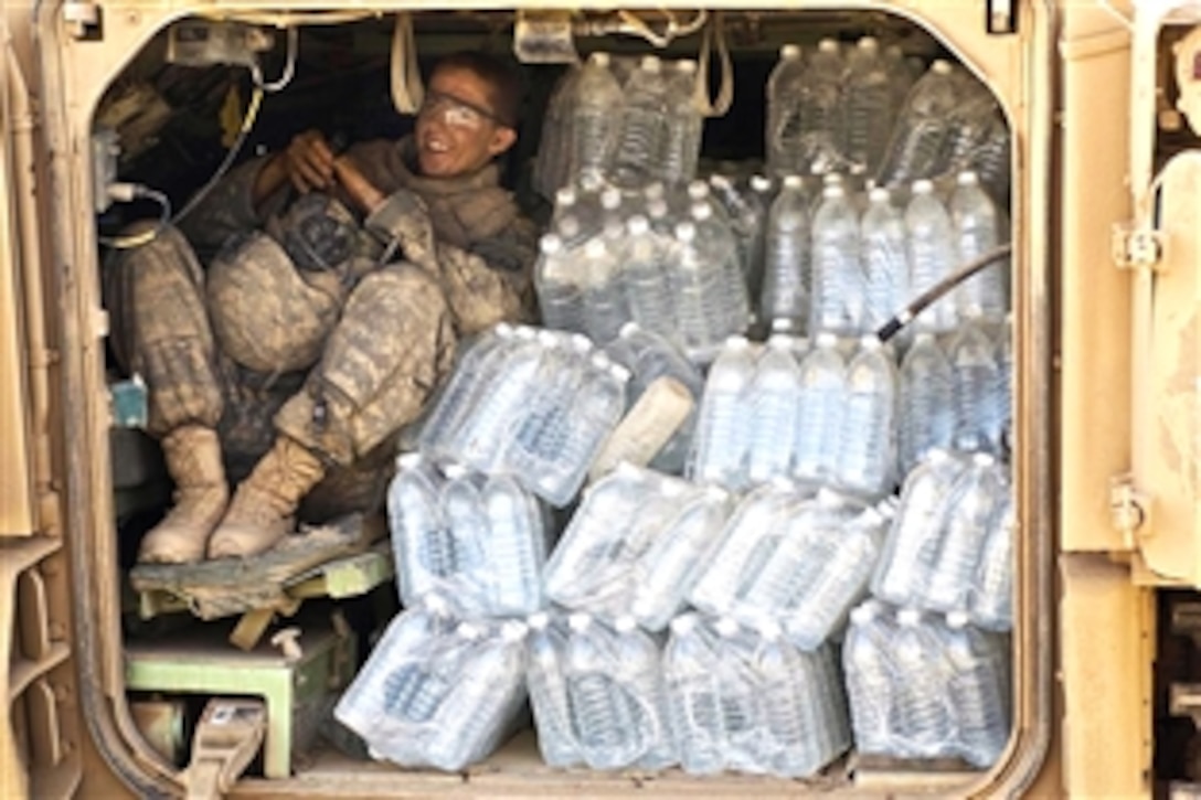 U.S. Army Pfc. Holtzhauser squeezes in next to several cases of water bottles in his Bradley Fighting Vehicle in Diyala, Iraq, July 13, 2008. Holtzhauser is assigned to the 3rd Armored Cavalry Regiment's Troop G, 2nd Battalion.


