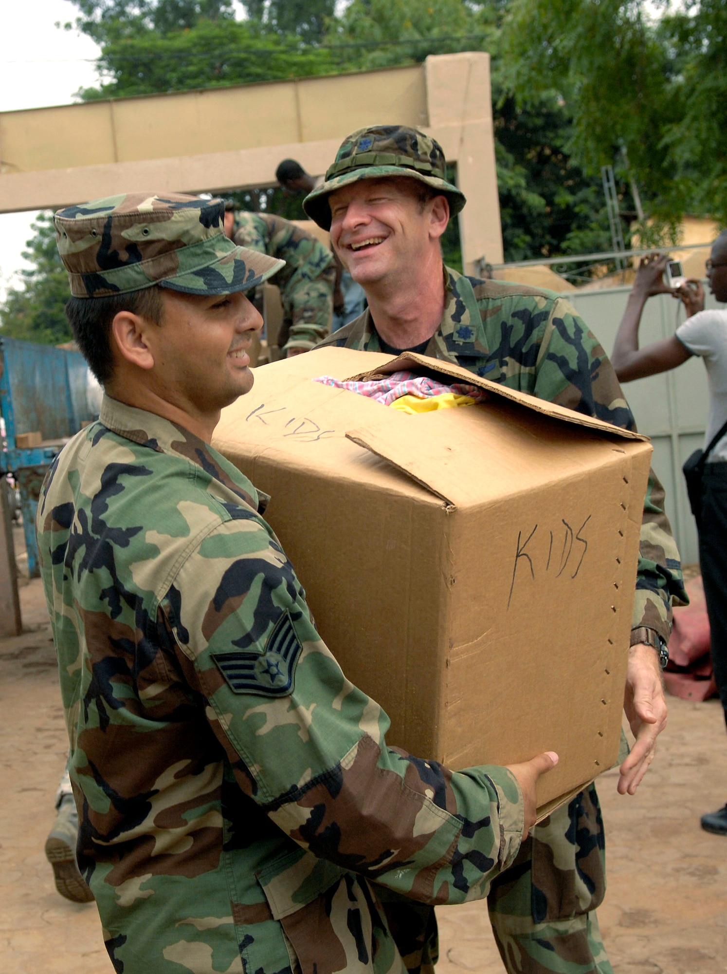 Lt. Col. Joseph Connolly hands Staff Sgt. Carlos Lomeli a box of children's clothing to be donated to the Bamako National Orphanage July 16. Airmen from the 31st Medical Group at Aviano Air Base, Italy, collected more than 2,500 pounds of clothing, toys and shoes to distribute at Bamako orphanages. Colonel Connolly is deployed from the 31st Medical Group at Aviano AB. Sergeant Lomeli is deployed from the 48th Medical Group at Royal Air Force, Lakenheath, England. (U.S. Air Force photo/Senior Airman Michael S. Dorus)