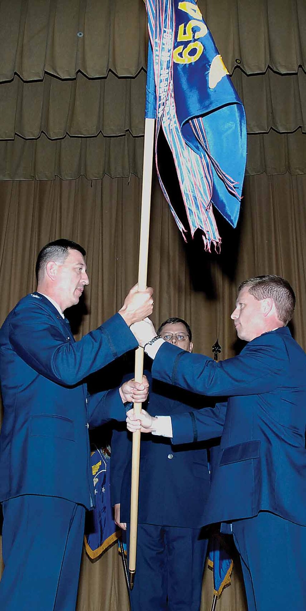 Maj. Robert Copes, 654th Combat Logistics Support Squadron commer, passes the guidon to Col. Casey Hughson, 76th Aircraft Maintenance Group commander, to inactivate the 654th CLSS and transfer the workload to the 76th AMXS.  (Air Force photo by Kelly White)