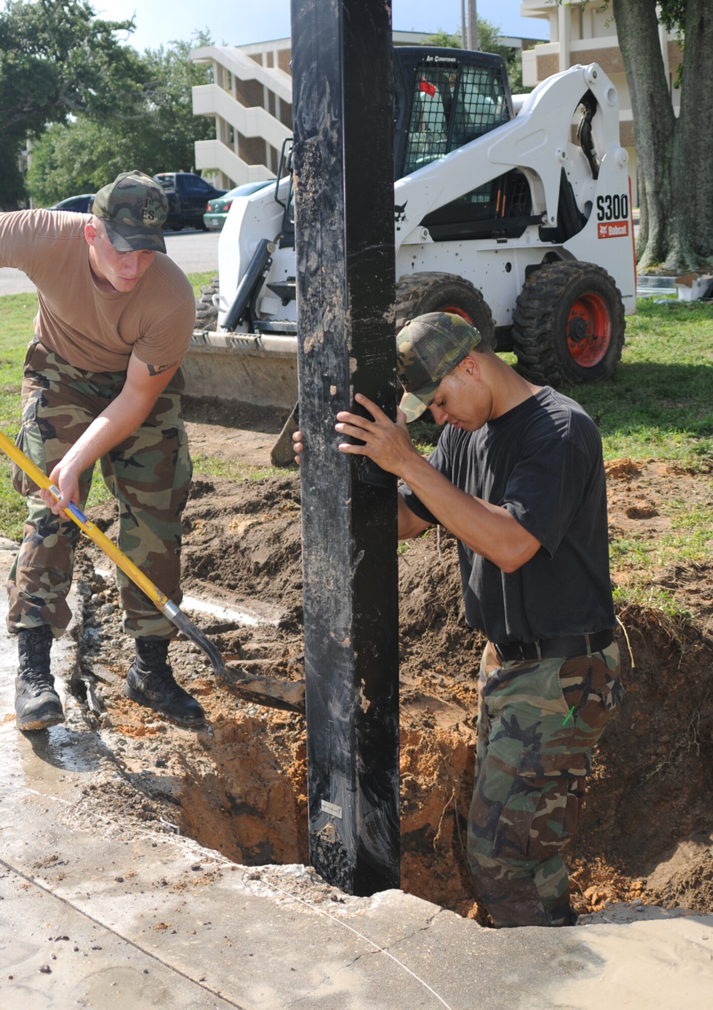 Airmen 1st Class Jeremy Landis, left, and Samuel Johnson, 81st Civil Engineer Squadron, pack dirt around a new basketball goal post before concrete is poured behind the permanent party dormitories on Larcher Boulevard July 10.  The new court is another in a series of quality-of-life improvements for dorm dwellers.  (U.S. Air Force photo by Kemberly Groue)