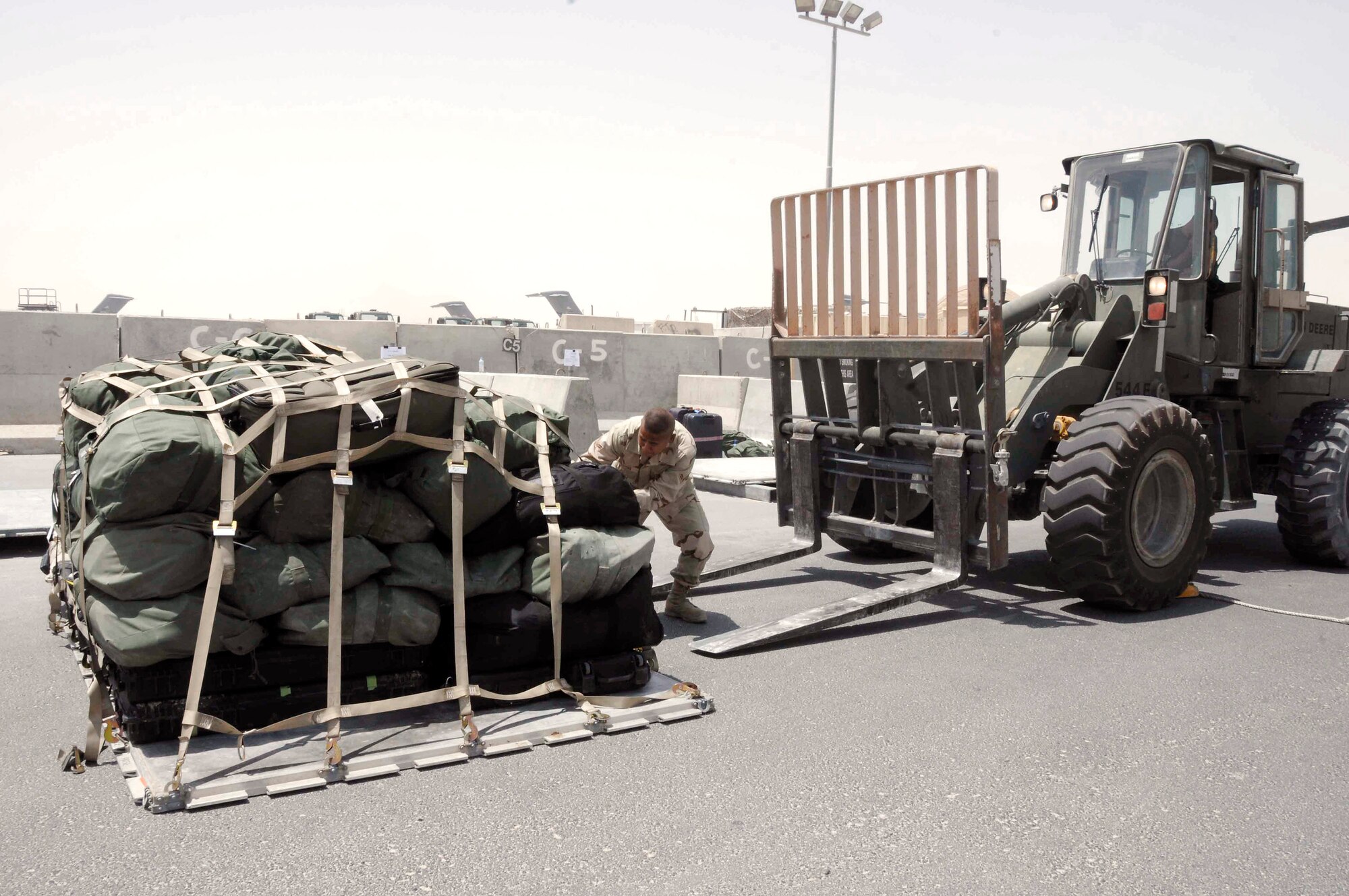 Airman 1st Class Zachary Weakly helps a wingman guide a pallet mounted forklift onto a carrier for loading July 8 in Southwest Asia. Airman Weakly is an Air National Guard member deployed from Stratton Air National Guard, N.Y. with the 8th Expeditionary Air Mobility Squadron and is from Duanesburg, N.Y. (U.S Air Force photo/Senior Airman Domonique Simmons) 