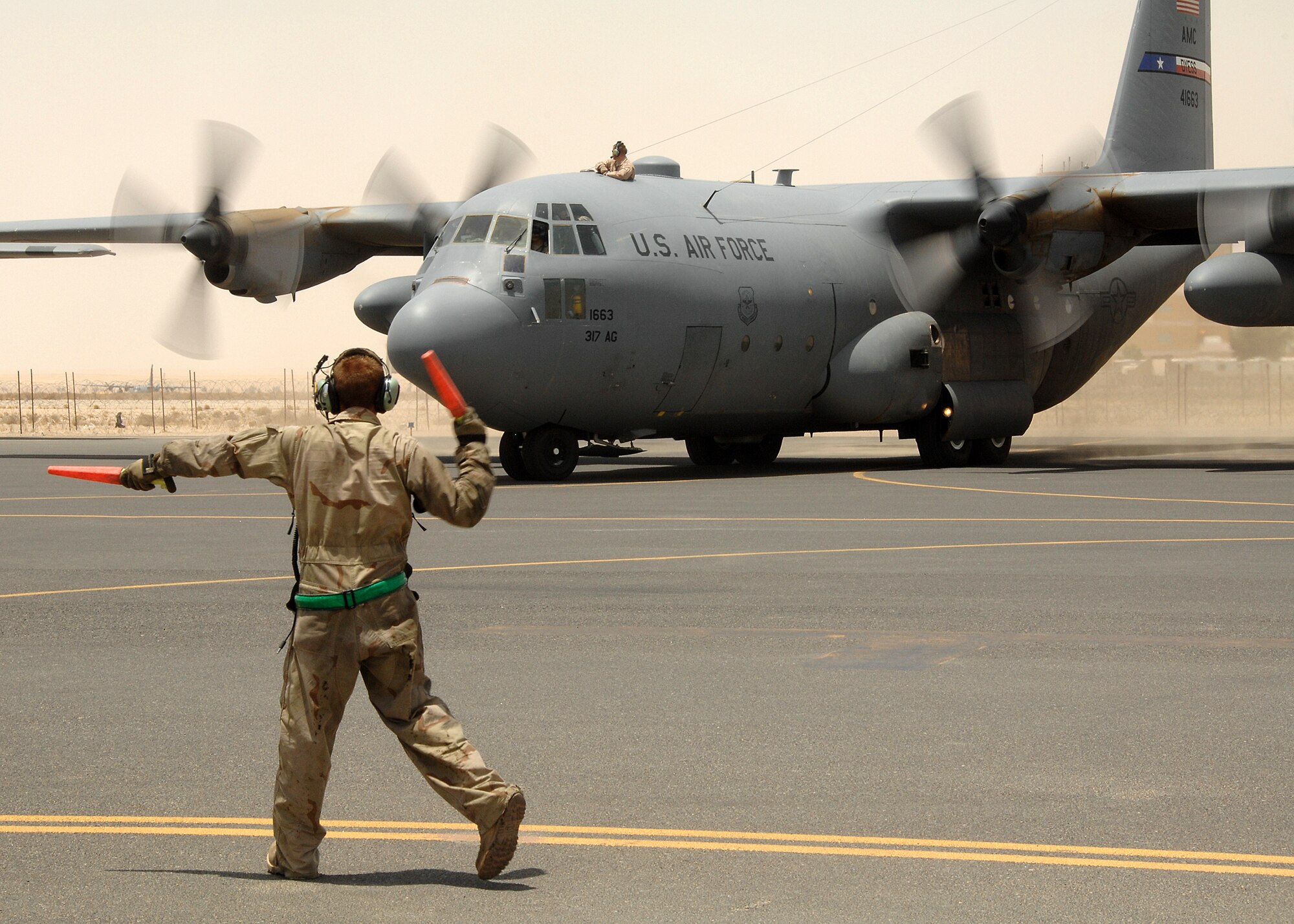 SOUTHWEST ASIA -- Senior Airman Marc Botts, a crew chief assigned to the 386th Expeditionary Aircraft Maintenance Squadron, marshals a C-130 Hercules off the parking ramp on July 17 at a base in Southwest Asia. Airman Botts is deployed from the 317th Airlift Group, Dyess Air Force Base, Texas. (U.S. Air Force photo/Tech. Sgt. Raheem Moore)