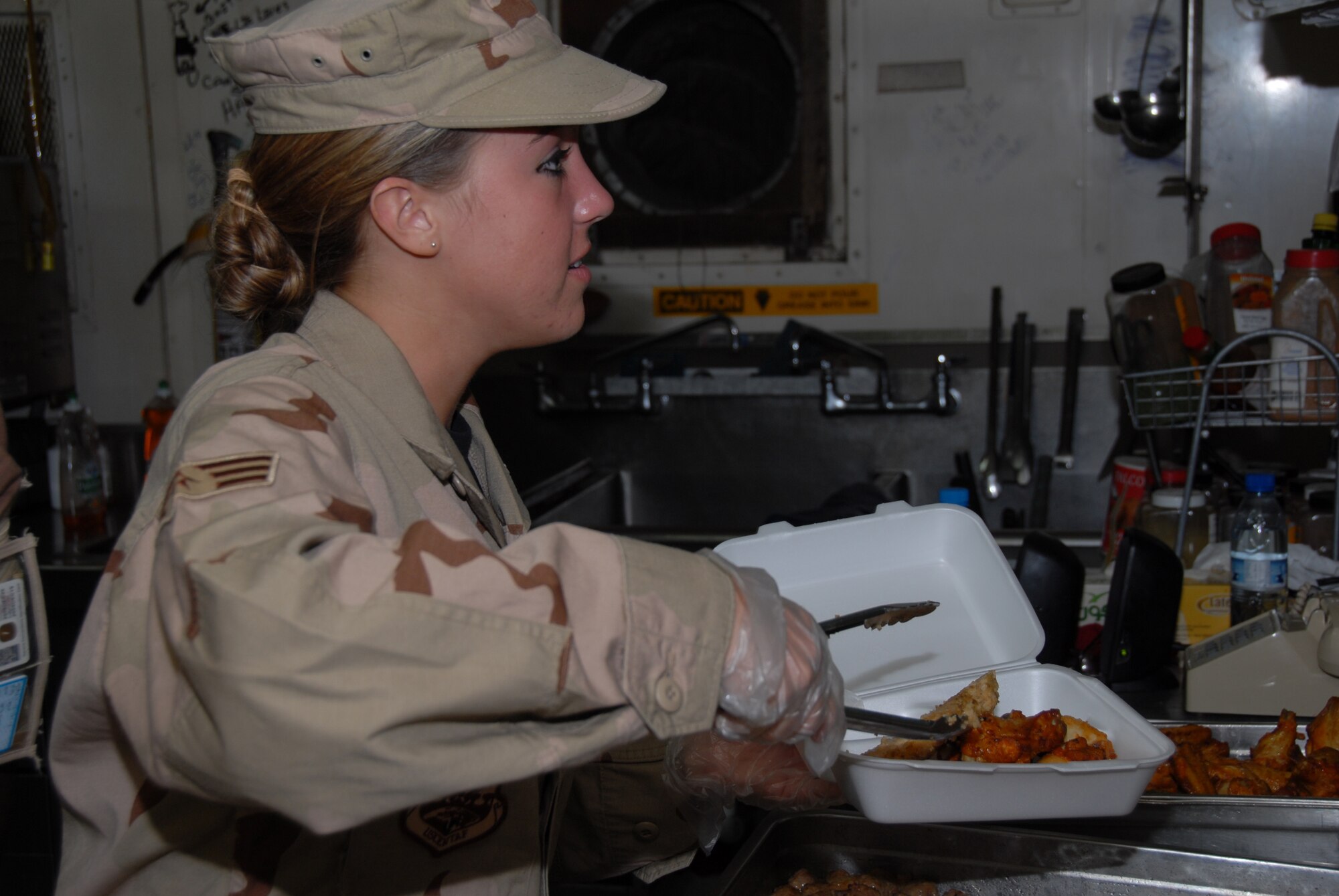 SOUTHWEST ASIA-- Senior Airman Melissa Woodhull from the 380th Force Support Squadron serves food during the lunch rush at Roy's Diner here recently. Airman Woodhull is deployed from the New Jersey Air National Guard and works at the flight line dining facility providing meals around the clock for several Airmen that work on or around flight operations. (U.S. Air Force photo/Tech. Sgt. Christopher A Campbell)(released)
