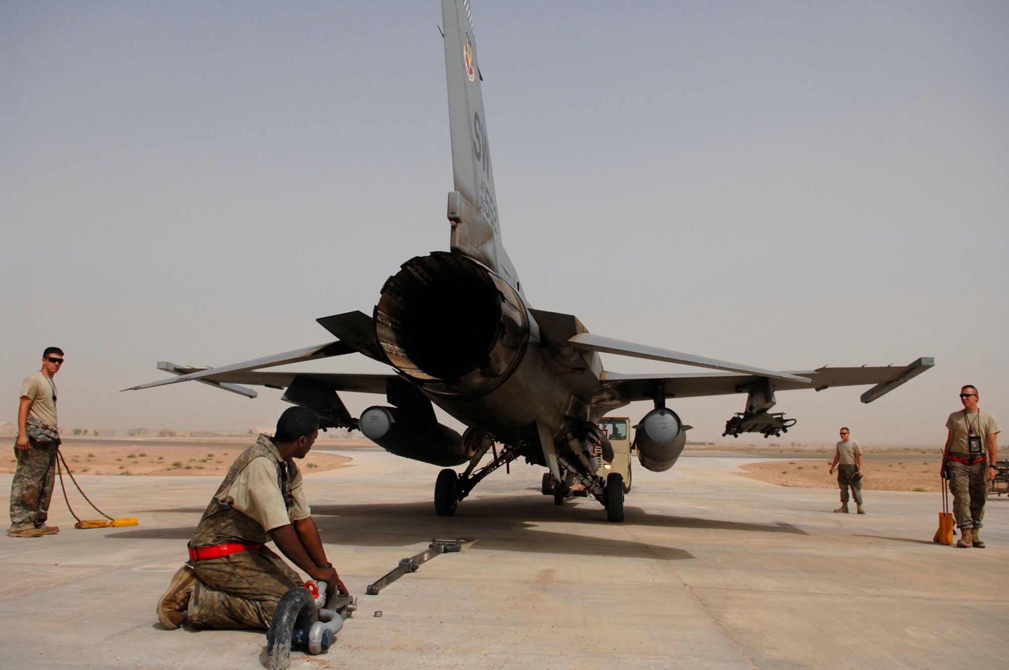 JOINT BASE BALAD, Iraq -- Members of the 77th Aircraft Maintenance Unit position an F-16 Fighting Falcon for an engine run up here July 16. The links and bar attached to the arresting hook secures the aircraft to the ground to prevent any movement and ensure the safety of the Airmen on the ground. The run up of the engine to full afterburner allows the engine mechanics and crew chiefs to ensure all systems are fully functional before putting the fighter back into operational use. The 77th AMU is deployed from Shaw Air Force Base, S.C. (U.S. Air Force photo/Senior Airman Julianne Showalter)