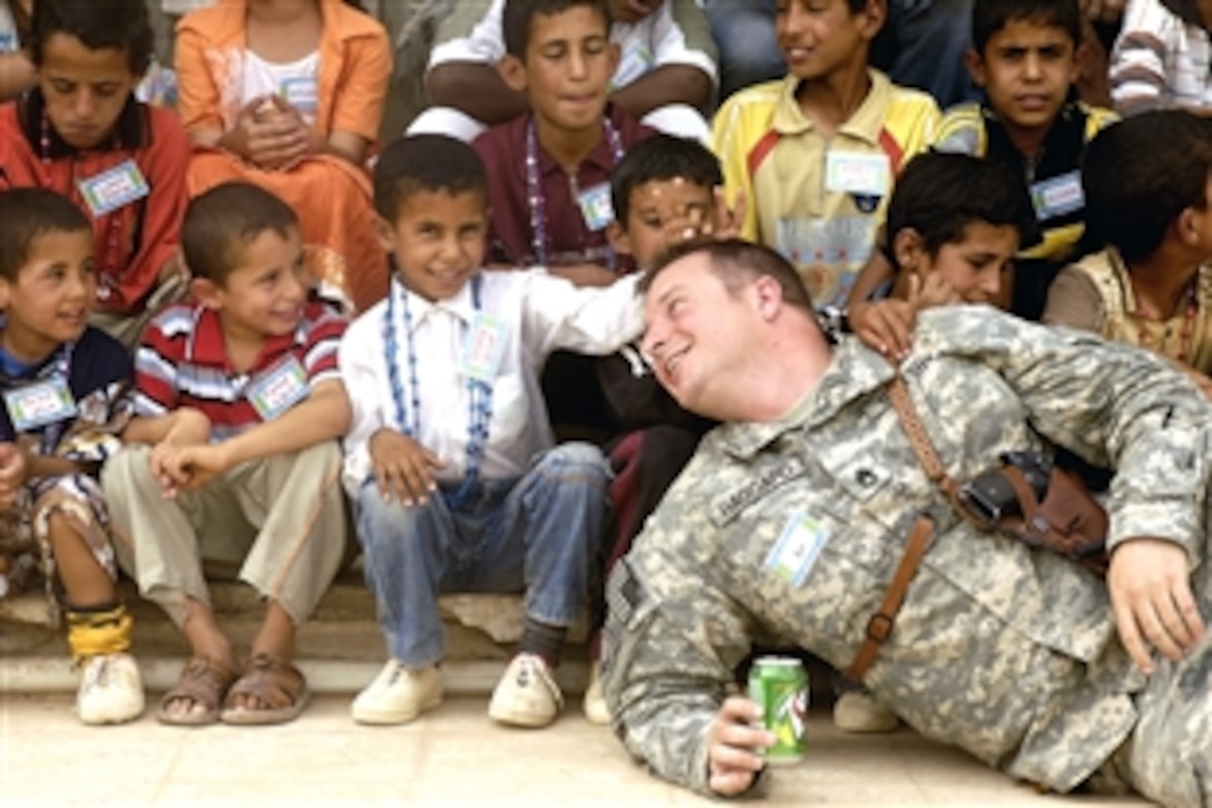 Iraqi children gather around U.S. Army Staff Sgt. Haggard  for a group photo during Youth Outreach Day on Contingency Operating Base Speicher, Tikrit, Iraq, July 12, 2008. The Provincial Reconstruction Team coordinated the event to increase understanding of coalition forces for children in the local community. 