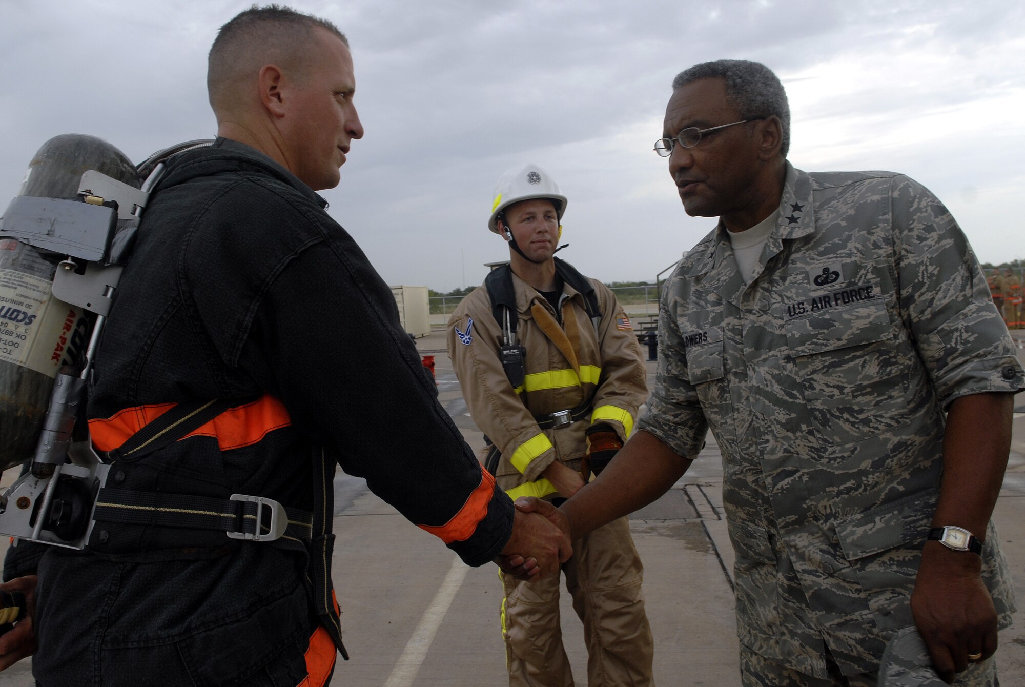 Staff Sergeant William Gates receives a handshake from Gen. Flowers, after completing the firefighter obstacle course. Sergeant Gates is a member of the SAM Squad firefighter challenge team and is ranked 8th in the world. (U.S. Air Force photo by Senior Airman Kamaile Chan) 