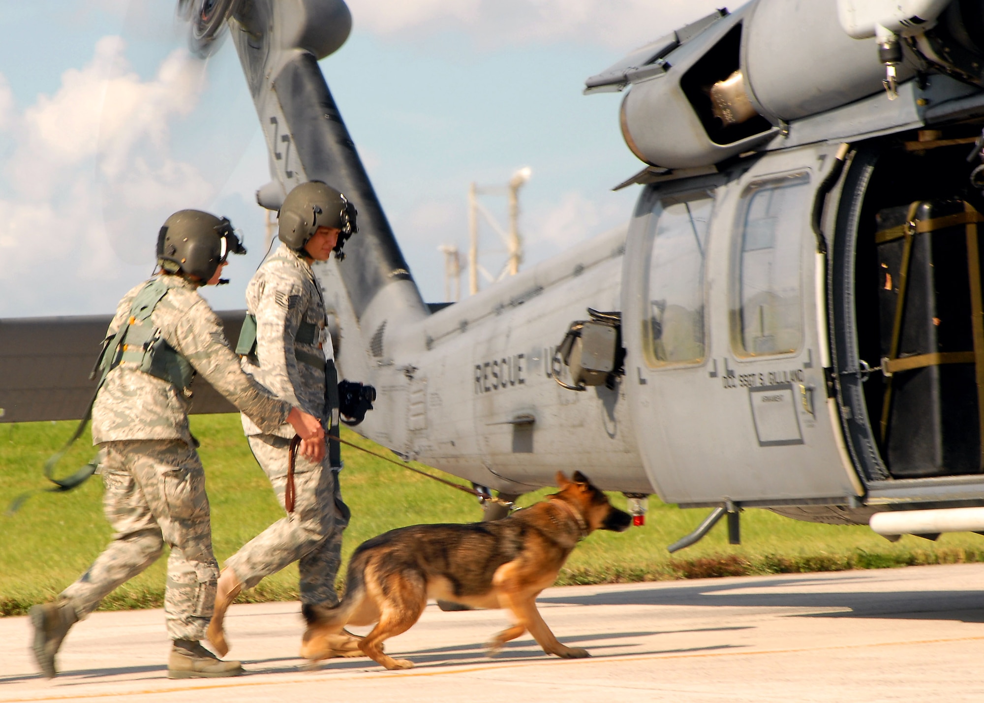 Staff Sgt. Sarah Merklinger restrains Bojar, a military working dog, on their way to board an HH-60 Pavehawk helicopter at Kadena Air Base, Japan, July 14. Kadena's working dogs participated in familiarization training to get used to the loud noise from helicopters and disturbances associated with flying during deployments. Sergeant Merklinger is a dog handler from the 18th Security Forces Squadron,.(U.S. Air Force photo/Airman Chad Warren)
