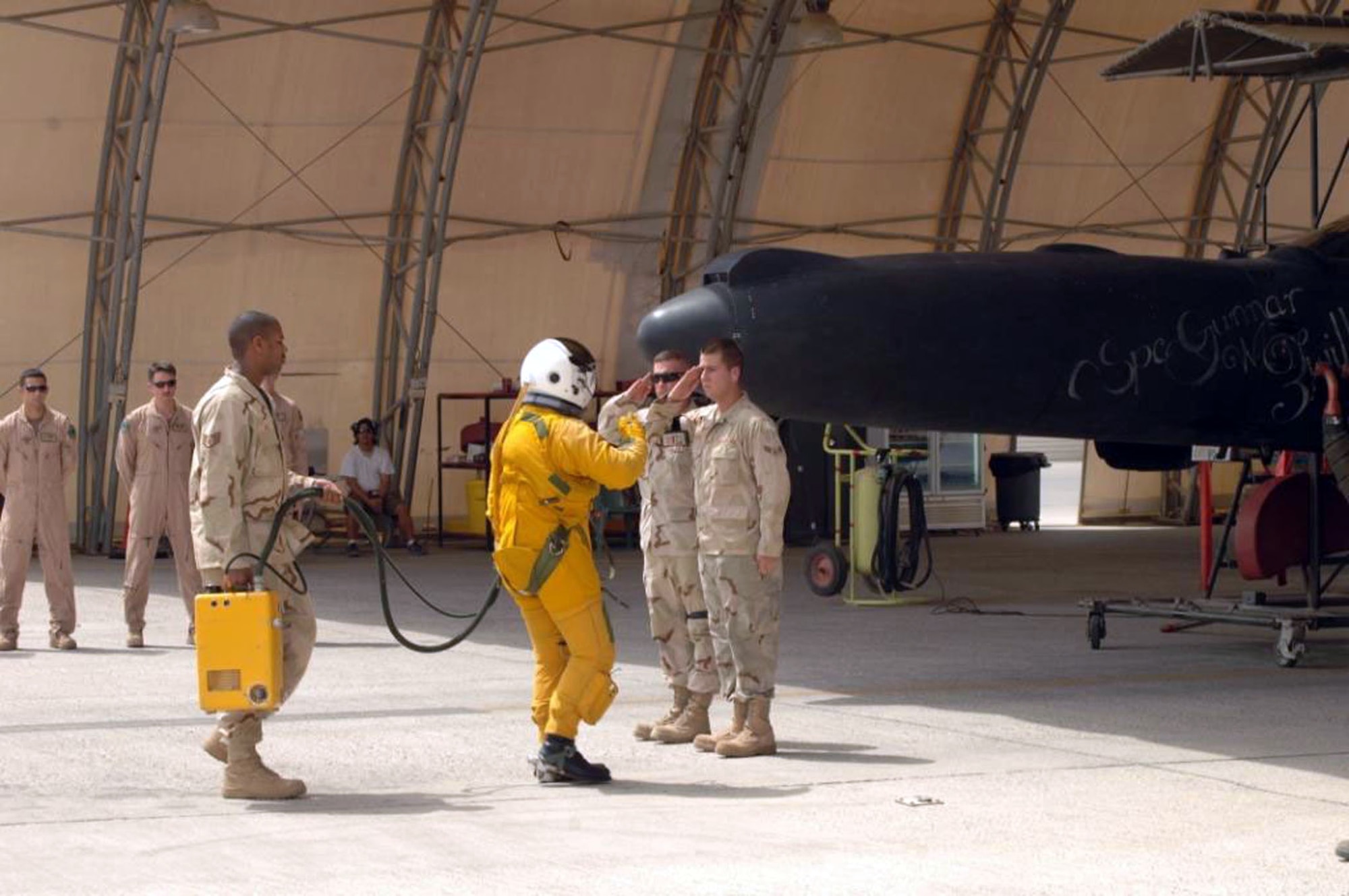 A1C Alexander Zwilling (r) and a co-worker salute a pilot before he flies a U-2 featuring chalk art honoring the Airman's brother, a Soldier who was killed July 13, 2008, in Afghanistan.