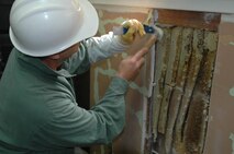 A group of bees mill around outside the entrance to the “false hive” the entrance is one-way, forces the bees that enter to remain the in hive. (U.S. Air Force photo/Senior Airman Shaun Emery)