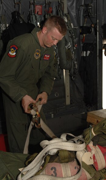 DYESS AIR FORCE BASE, Texas -- Airman 1st Class Zachary Farrell, a 39th Airlift Squadron loadmaster, finishes strapping down all loose cargo on a C-130 July 16 here. Airman Farrell was part of a 10-plane formation performed July 16. The C-130s dropped heavy equipment cargo, after the three-hour flight they landed at Dyess and dropped goverment vehicles out of the cargo bay, before taking off and looping around Dyess one more time.  (U.S. Air Force photo by Senior Airman Jennifer Romig)