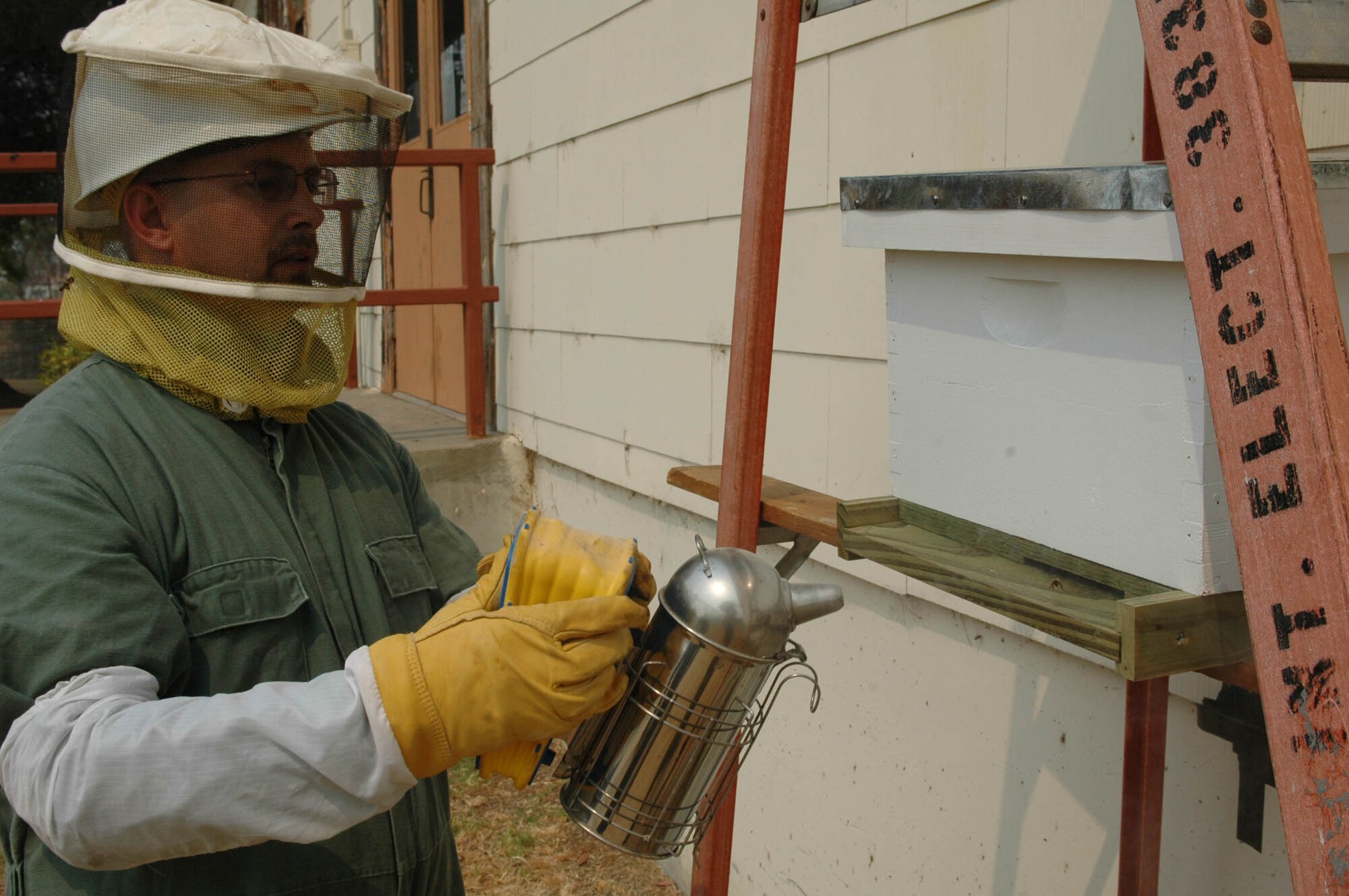 Mr. Robert Kennedy prepares to smoke the bees in the “false hive” prior to opening the hive. The smoke causes the bees to huddle together, believing there is a threat the hive and making it easier to work with them. (U.S. Air Force photo/Senior Airman Shaun Emery)
