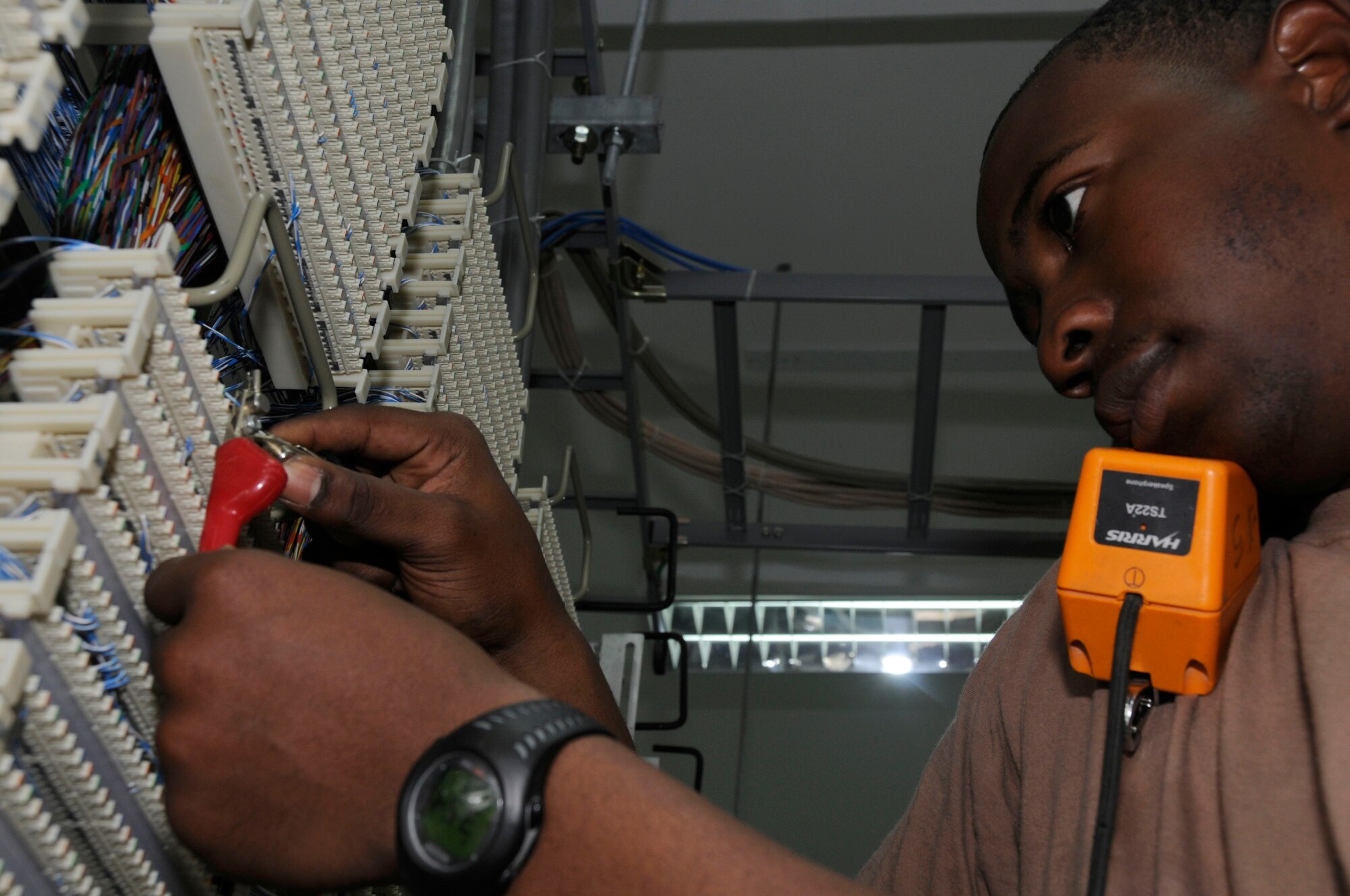 Airman Barry Williams, 379th Expeditionary Communications Squadron, uses the butt set to check for a dial tone here July 14. Airman Williams is a telephone maintainer deployed from Yokota Air Base, Japan. (U.S. Air Force photo by Staff Sgt. Darnell T. Cannady)