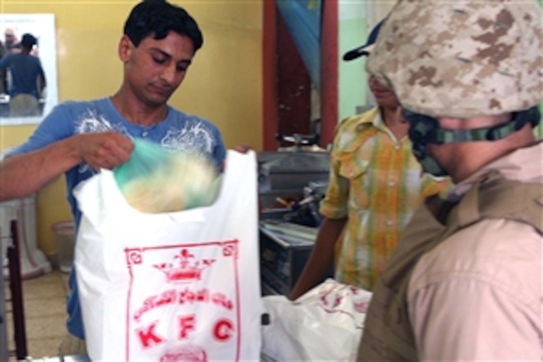 U.S. Marines pick up chicken to go from Iraqi employees at a Kentucky Fried Chicken restaurant in the Hey Al Dubat area of Fallujah, Iraq, July 16, 2008. This and other businesses have become popular with local residents as a result of security improvements in the area. 