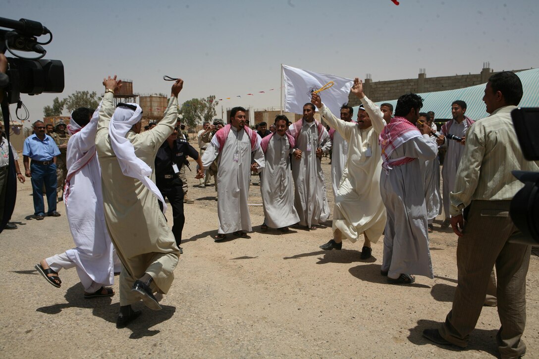 Iraqi men attending the opening of the K3 Oil Refinery near Haditha, Iraq, July 18, perform a ceremonial dance to celebrate the event. The refinery will open up employment in the Haditha area and provide cheaper fuel for the Iraqi people in Western Iraq. Marines with 3rd Battalion, 4th Marine Regiment, Regimental Combat Team 5 provided security for the event.::r::::n::