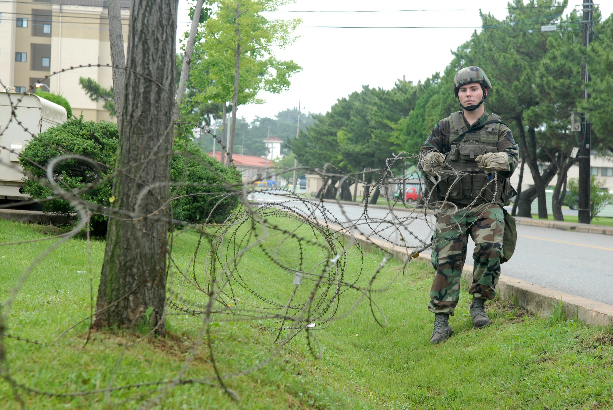 KUNSAN AIR BASE, Republic Of Korea  --  Airman 1st  Class Rian Jones, 8th  Security Forces Squadron, unwinds and places concertina-wire around a building during the BEVERLY BULLDOG 08-03 peninsula-wide operational readiness exercise here July 21st. The PENORE is a 7th Air Force led training exercise deigned to keep Wolf Pack and other U.S. Airmen in Korea ready to execute the mission. (U.S. Air Force photo by: Senior Airman Angela Ruiz)