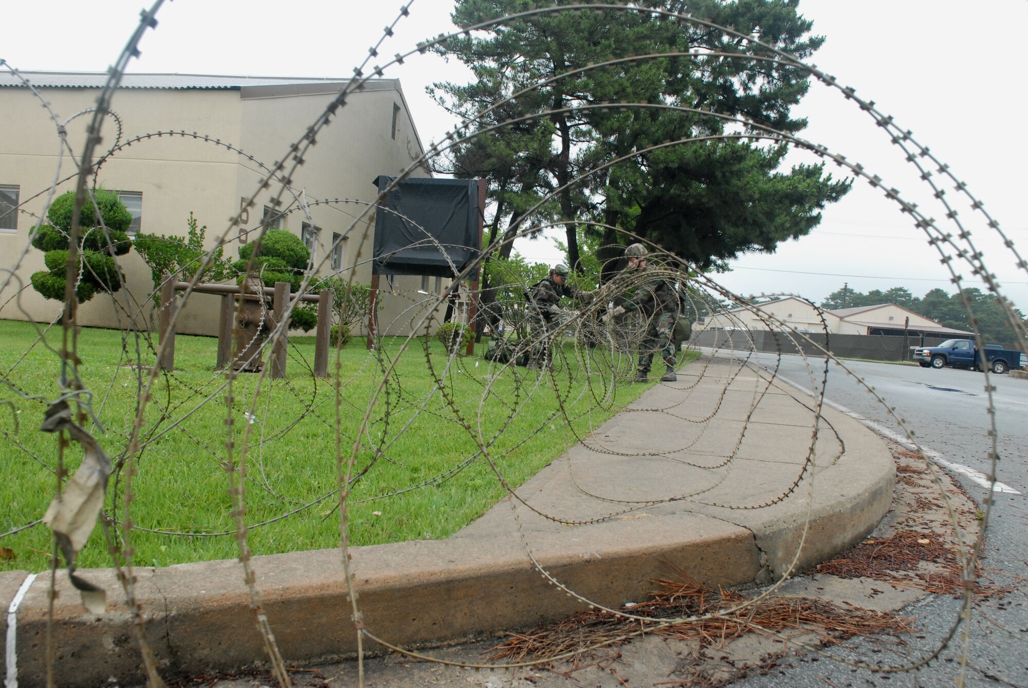 KUNSAN AIR BASE, Republic Of Korea  --  Airmen 1st Class Ruth Torres and Rian Jones, 8th  Security Forces Squadron, unwind and place concertina-wire around a building during the BEVERLY BULLDOG 08-03 peninsula-wide operational readiness exercise here July 21. The PENORE is a 7th Air Force led training exercise deigned to keep Wolf Pack and other U.S. Airmen in Korea ready to execute the mission. (U.S. Air Force photo by: Senior Airman Angela Ruiz)