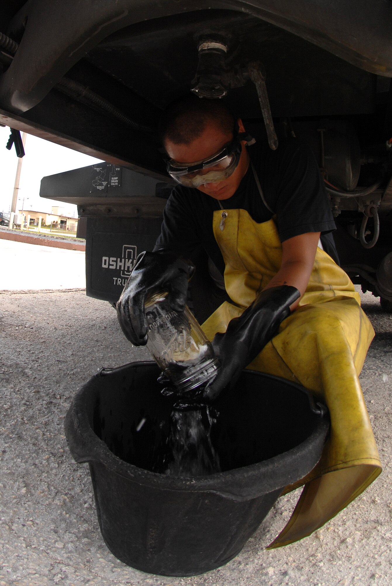 Airman 1st Class John Nguyen drains a quart of jet fuel at a vehicle check station here July 14. A quart of fuel was drained and visually checked for sediments and water before allowing the R-12 to deliver fuel to the flight line. The main purpose for this check is to insure that clean, dry fuel is pumped into the aircrafts. (U.S. Air Force photo by Airman 1st Class Courtney Witt)