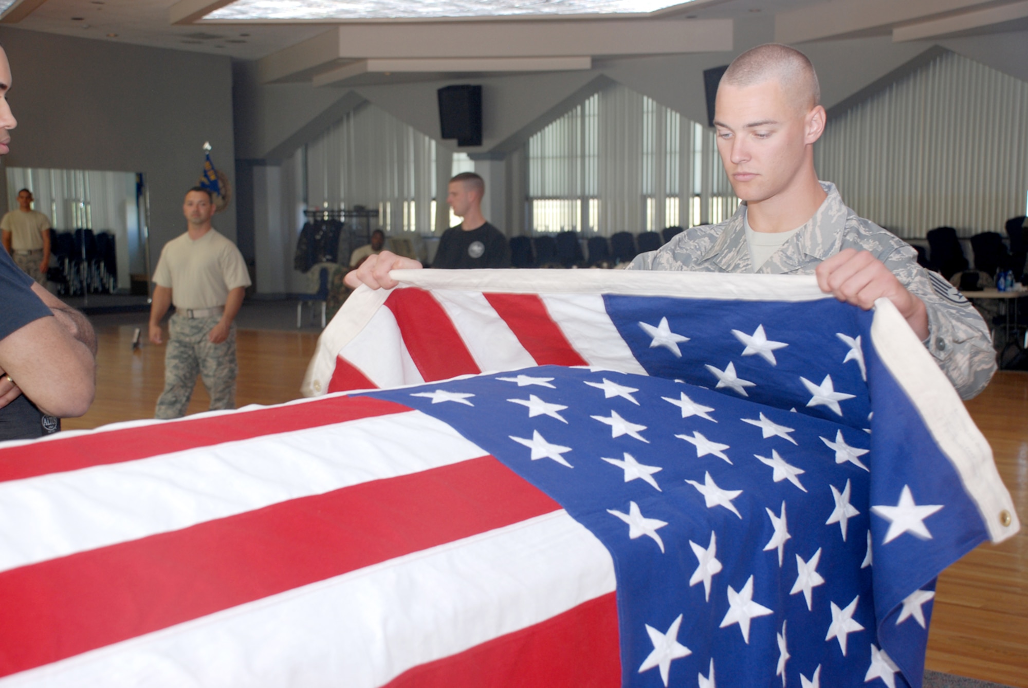 Staff Sgt. Alex Frizzo, USAF Honor Guard, drapes the American flag over the casket in preparation of a pall bearing class. The classes were broken into three groups based on experienced, who each were taught the different functions of active-duty funerals. 
