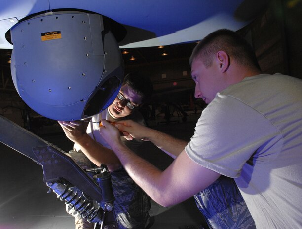 Staff Sgt. Shaun Johnson (background), a MQ-1 Predator crew chief and Senior Airman Eric Hurley, a MQ-1 Predator avionics specialist, both assigned to the 163rd Aircraft Maintenance Squadron March Air Reserve Base, Calif., inspects the cover of the sensor on a MQ-1 Predator July 10, 2008 Creech Air Force Base, Nev. Staff Sgt. Johnson and Senior Airman Hurley are part of a three man team of reservists from March here on temporary duty to receive a month long of training alongside there active duty counterparts before deploying to Southwest Asia.(U.S. Air Force Photo by/Senior Airman Larry E. Reid Jr., Released)