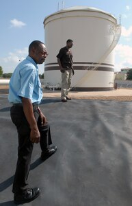Dennis Stewart (left), fuels quality assurance flight supervisor, and Robert Woodfork, a fuels technician, inspect contractors downloading JP-8 jet fuel at the bulk fuels storage facility near the flightline July 17. (U.S. Air Force photo by Rich McFadden)