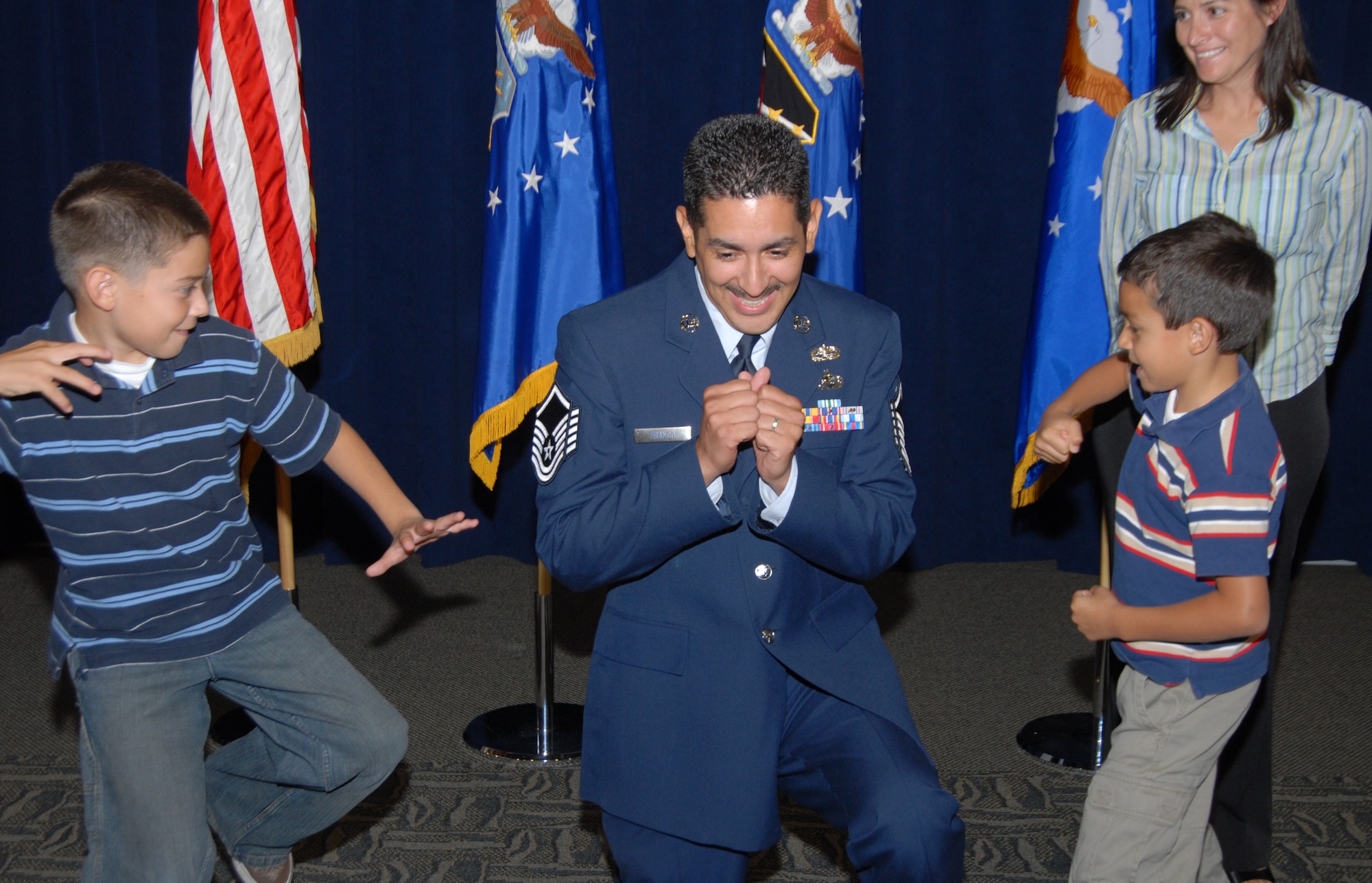 Promotee to Master Sergeant, Peter Franco, Space Superiority Systems Wing, gets his traditional punch in the arm by his sons, Nico (left) and Emilio, as his wife, Kathy, watches during the monthly recognition and promotion ceremony, June 30.  (Photo by Joseph Juarez)