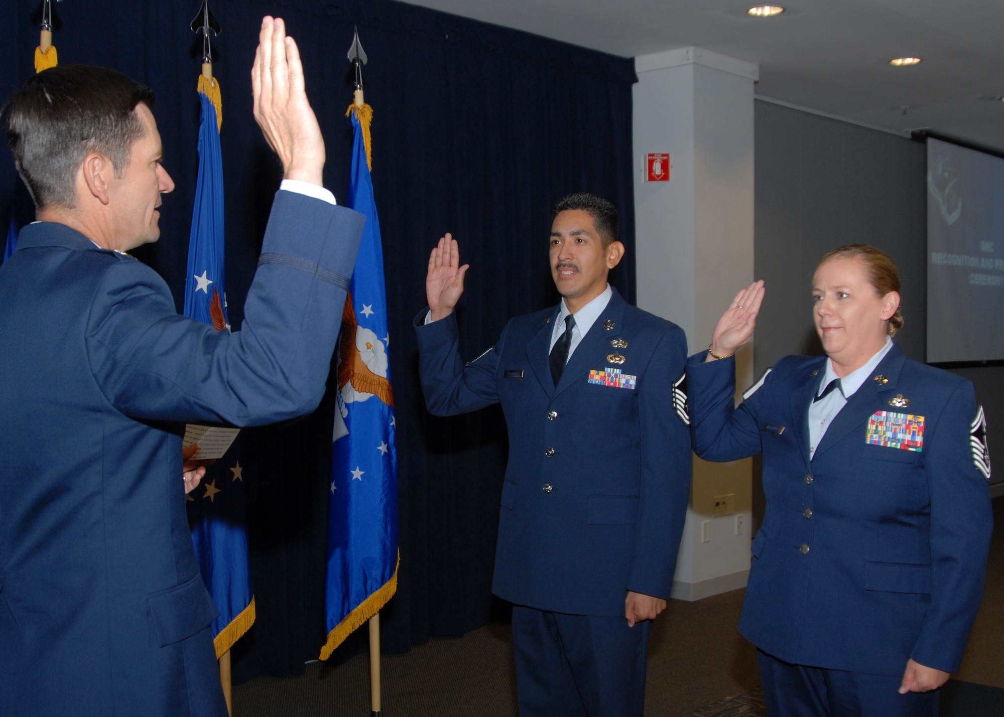 (left to right) Col. Joseph Schwarz, 61st Air Base Wing commander, assists promotee to Master Sergeant, Peter Franco, Space Superiority Systems Wing, and promotee to Senior Master Sergeant, Lori Vrooman, Space and Missile Systems Center Office of the Staff Judge Advocate, reaffirm their Oath of Enlistment during the monthly recognition and promotion ceremony held at the Gordon Conference Center at Los Angeles Air Force Base, June 30.  (Photo by Joseph Juarez)