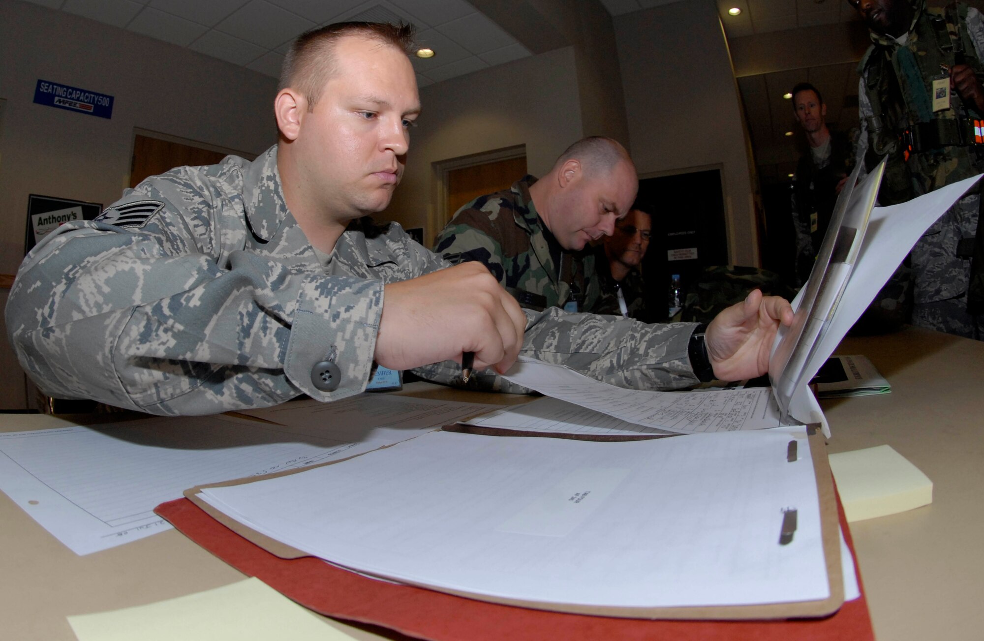 KUNSAN AIR BASE, Republic of Korea -- Staff Sgt. Daniel Swindle, 8th Fighter Wing personnel deployment reception function team member, reviews mobility folders as Airman prepare to forward deploy to locations throughout Korea during BEVERLY BULLDOG 08-03, a peninsula-wide operational readiness exercise here July 21. The personnel deployment reception function line is use to check accountability and make sure all required training is completed before deployment.  (U.S. Air Force photo by Senior Airman Dana Hill)