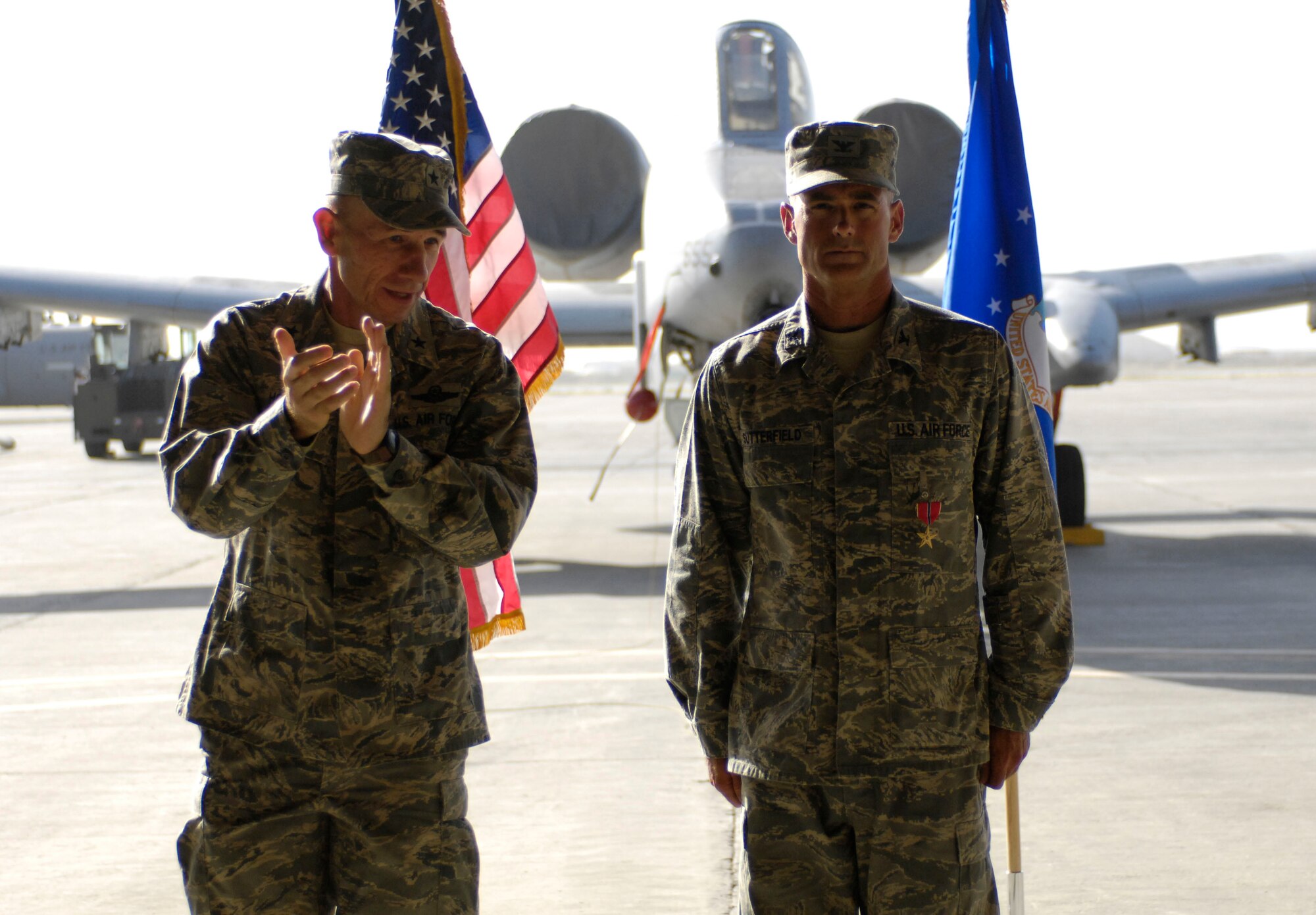 BAGRAM AIR FIELD, Afghanistan -- Brig. Gen. Mike Holmes, 455th Air Expeditionay Wing commander, applauds Col. Jon Sutterfield, 455th Expeditionary Maintenance Group commander, after awarding him the Bronze Star Medal during a change of command ceremony here July 17, 2008. Colonel Sutterfield earned the Bronze Star Medal for his leadership and accomplishments as the 455th EMXG commander from Aug. 8, 2007 to July 17, 2008. (U.S. Air Force photo by Staff Sgt. Rachel Martinez)