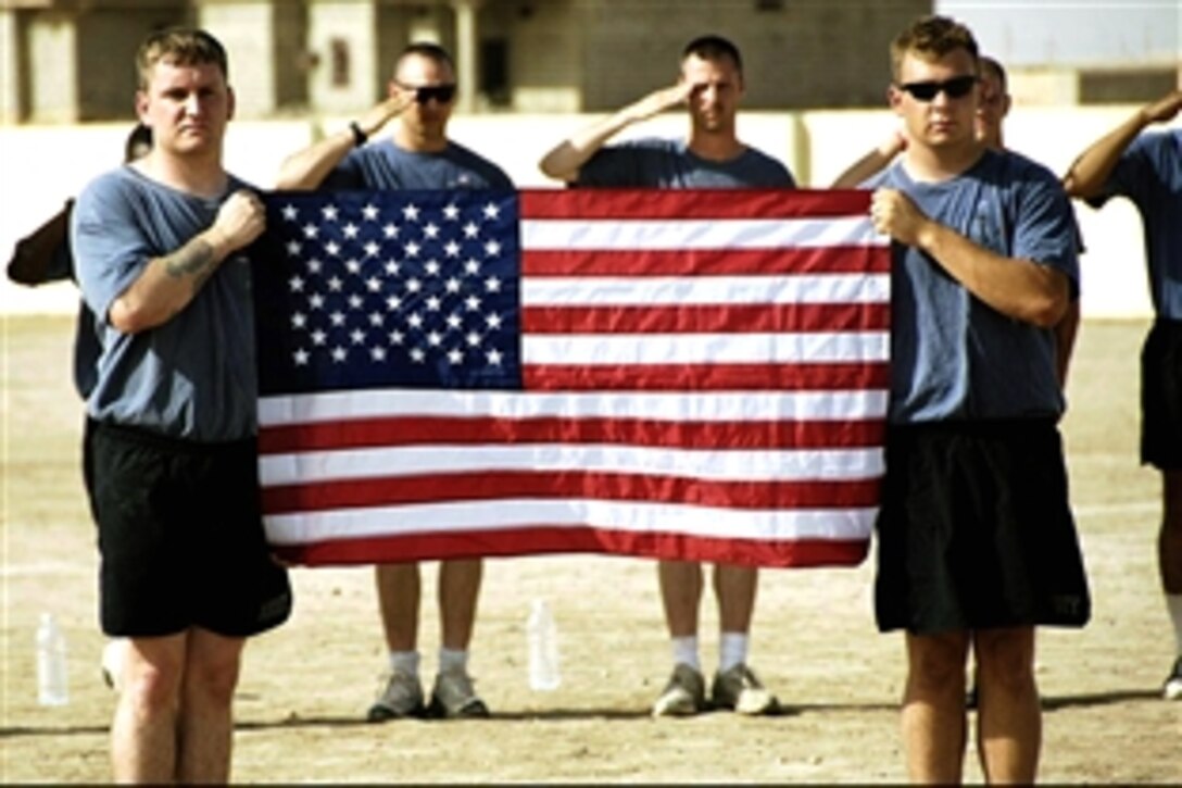 Two U.S. Army soldiers hold up the American flag during the playing of the national anthem before a soccer game between U.S soldiers and citizens of Zaab, Iraq, July 11, 2008. The soldiers are assigned to the 101st Airborne Division's 1st Battalion, 87th Infantry Regiment, and have played a series of soccer games with Iraqi teams. 