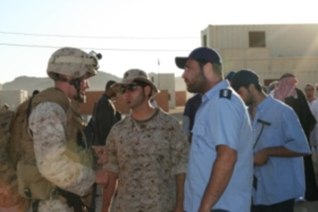 Suheil Sitto (center), a civilian interpreter and Iraq-native, enables Capt. Joseph Graves, a platoon commander with Company G, 2nd Battalion, 25th Marine Regiment to communicate with an Iraqi Police officer (role player) to work together to quell civil unrest in a notional Iraqi town constructed at Marine Corps Air-Ground Combat Center in Twentynine Palms, Calif. Role players and interpreters are used to add a sense of realism to the pre-deployment training for the Marines. The July 21, 2008 training event marked the end of a week-long, battalion-level training evolution for the battalion, which is headed to Iraq this fall.