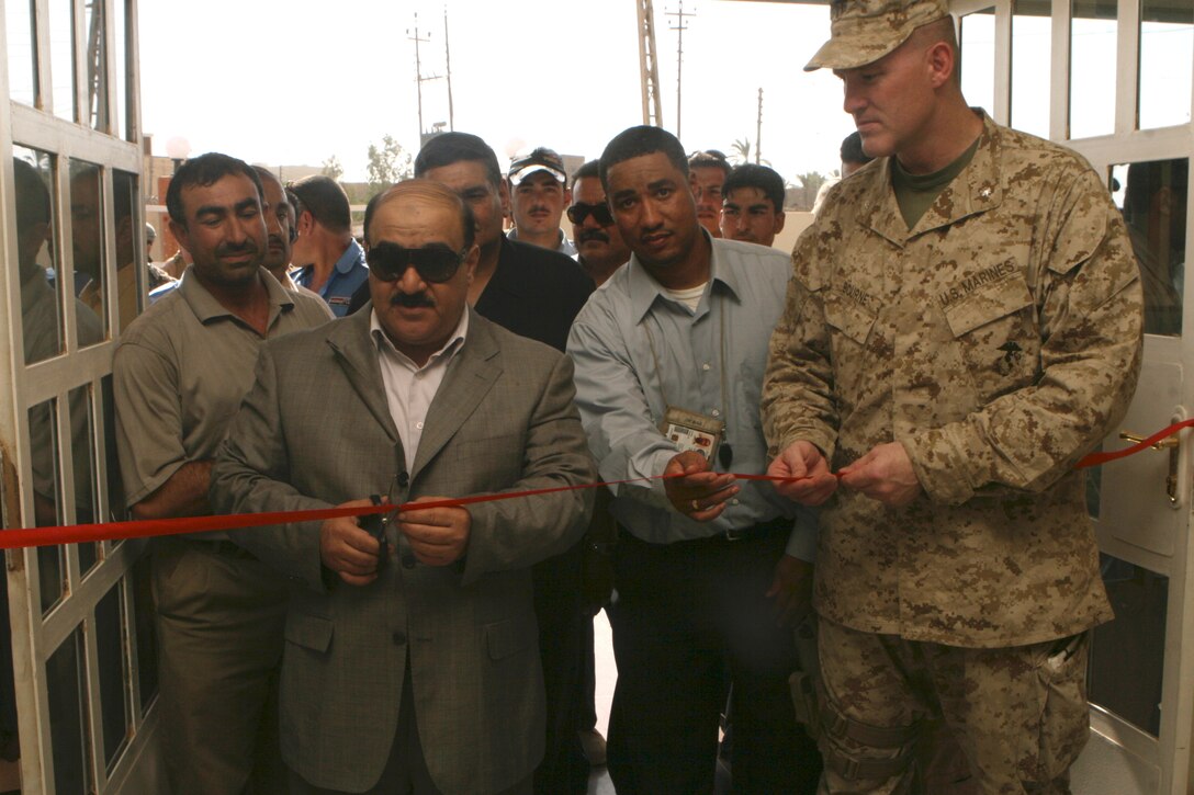 Ramadi Mayor Latif Obaid (center) cuts a ribbon during the reopening of the Ramadi Teacher’s Union Building July 21. (Official U.S. Marine Corps photo by Lance Cpl. Casey Jones)