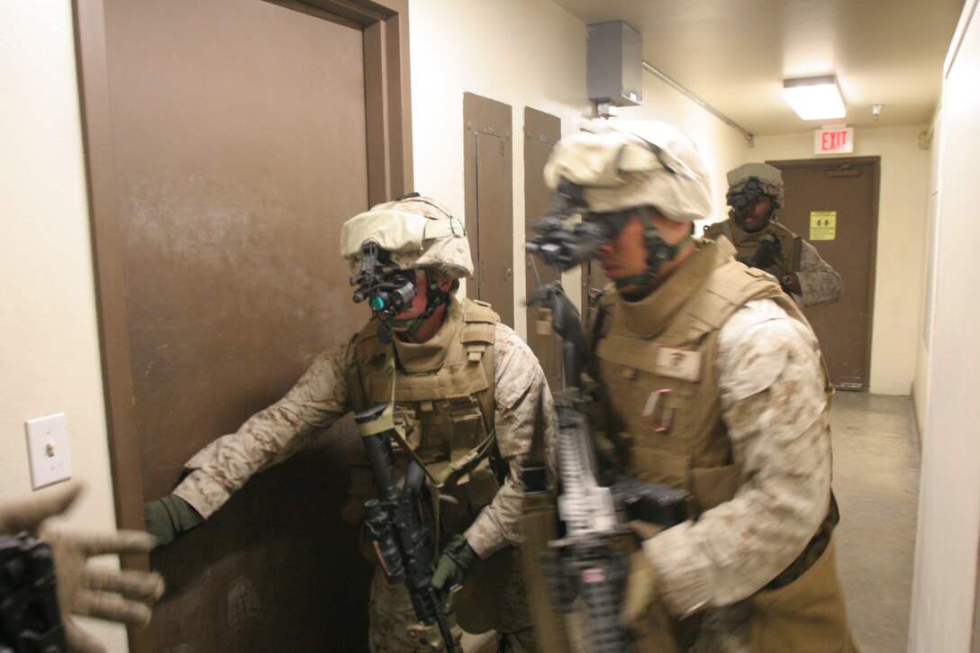 Pfc. Michael Patterson, an amphibious assault vehicle crewman with Delta Company, 3rd Assault Amphibian Battalion, and a native of Concord, N.C, throws open the door for Cpl. Diego Melendez, an Amtrak Operator with Delta Company, and a native of Compton, Calif. Room clearing was done Tuesday, July 22, 2008 as part of the night’s portion of the week-long training schedule.