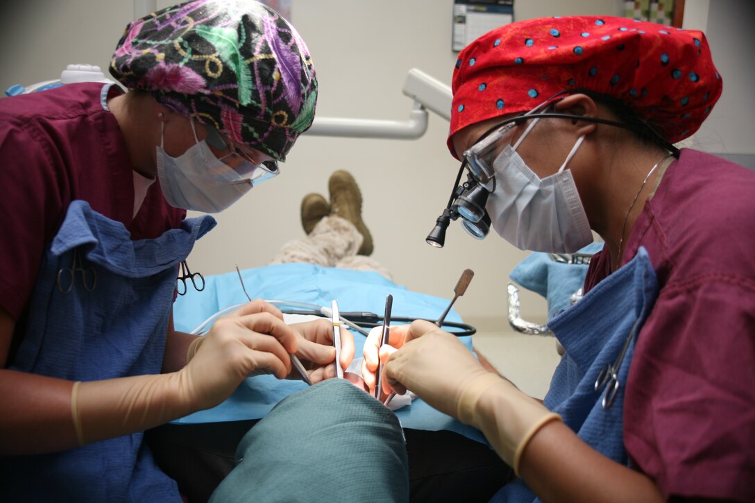 Ashley Lawson (left) and Cmdr. Grace Key perform a bone graft on a Marine at the Dental Clinic here. Lawson is a dental assistant and Key is the clinic periodontist.