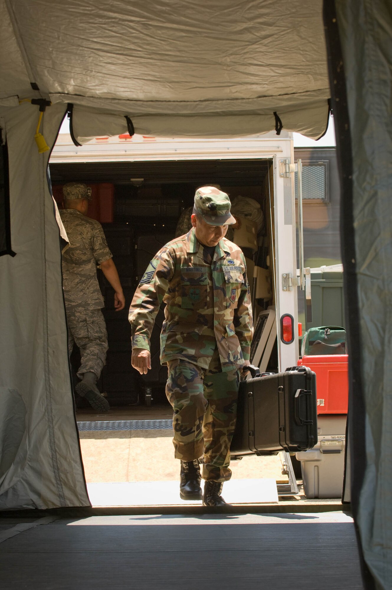 Master Sgt. Mark Martinez helps setup a base-X tent, part of the Joint Incident Communications Capability (JICC) that will provide video teleconference, satellite and cellular communications next to the Emergency Operations Center in San Antonio July 22. The Texas Army National Guard is part of the Standing Joint Interagency Task Force-Texas at Camp Mabry, Texas. Sergeant Martinez is from the Air National Guard's 149th Communications Flight at Lackland Air Force Base, Texas. Once completed the JICC will provide 2000 sq. ft. of portable or tented floor space on the lawns in front of the EOC. (U.S. Air Force photo/Lance Cheung)