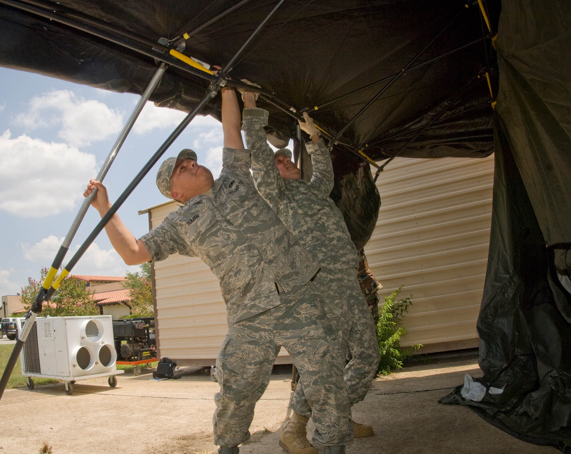 Staff Sgts. Gonzalo Roman and Robert Ribeiro setup a base-X tent, part of the Joint Incident Communications Capability (JICC) that will provide video teleconference, satellite and cellular communications next to the Emergency Operations Center at Brooks City-Base in San Antonio July 22.  The Texas Army National Guard is part of the Standing Joint Interagency Task Force-Texas at Camp Mabry, Texas.  Sergeant Ribeiro is from the Texas Army National Guard's Bee Caves Armory, Austin, Texas. Sergeant Roman is from the Air National Guard's 149th Communications Flight at Lackland Air Force Base, Texas. Once completed the JICC will provide 2000 sq. ft. of portable or tented floor space on the lawns in front of the EOC. (U.S. Air Force photo/Lance Cheung)