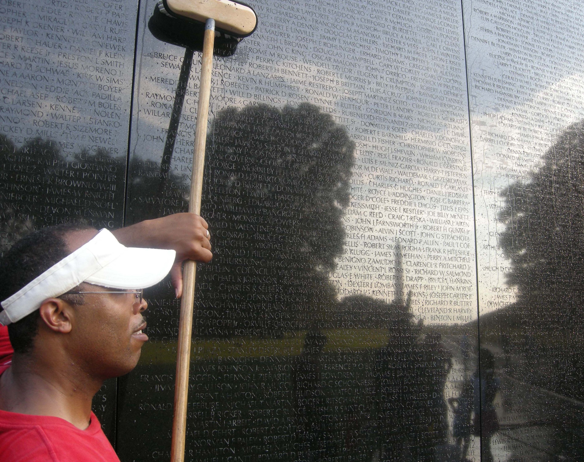 WASHINGTON -- Tech. Sgt. Roderick Branch, 459th Air Refueling Wing Chaplain Services Support member, scrubs fallen service members' names etched along the nearly 247-foot granite Vietnam Memorial Wall here July 20. The volunteer wall washing event is a way for service members to thank those who have made the ultimate sacrifice and is conducted under the guidance of the National Park Service. The NPS coordinates volunteers to clean the wall each week, or 52 times per year.  At dawn, more than 20 members of the 459th Air Refueling Wing, family and other volunteers stood face to face with their own reflections while washing more than 58,000 names of service members on the wall. (U.S. Air Force photo/Tech. Sgt. Amaani Lyle)