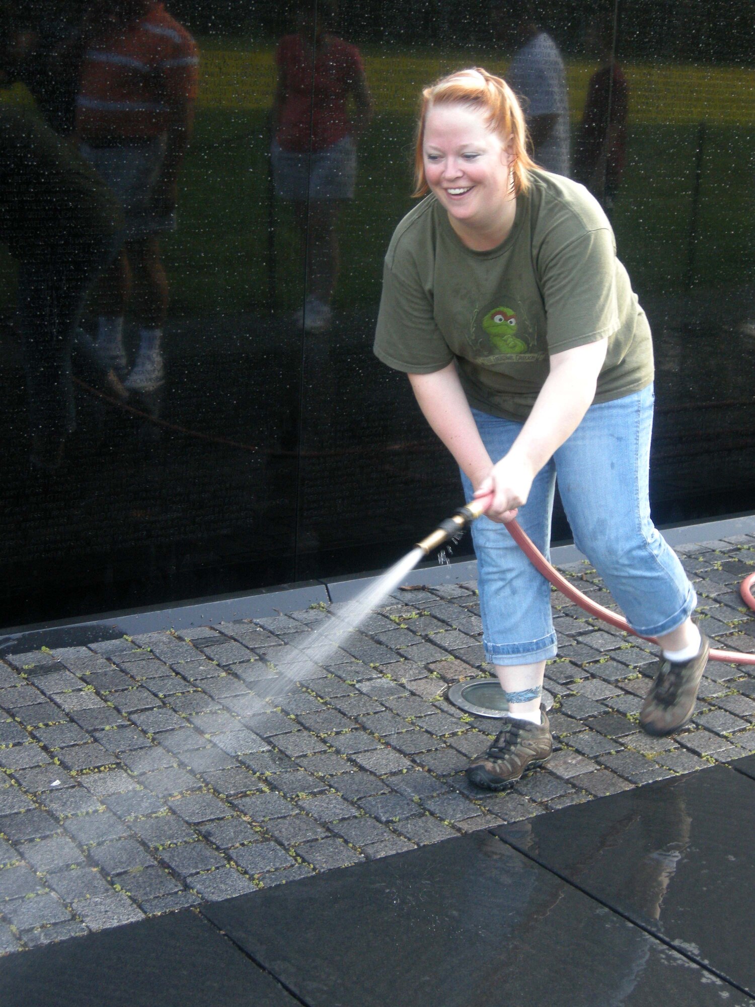 WASHINGTON -- Tech. Sgt. Shawn Shipp, 459th Air Refueling Wing Command Post security officer, hoses off a pathway that follows the nearly 247-foot Vietnam Memorial Wall at a 125-degree angle here July 20. The event is a way for service members to thank fallen service members and was conducted under the guidance of the National Park Service. The NPS coordinates volunteers to clean the wall each week, or 52 times per year.  At dawn, more than 20 members of the 459th Air Refueling Wing, family and other volunteers stood face to face with their own reflections while washing more than 58,000 names of service members on the wall. (U.S. Air Force photo/Tech. Sgt. Amaani Lyle)