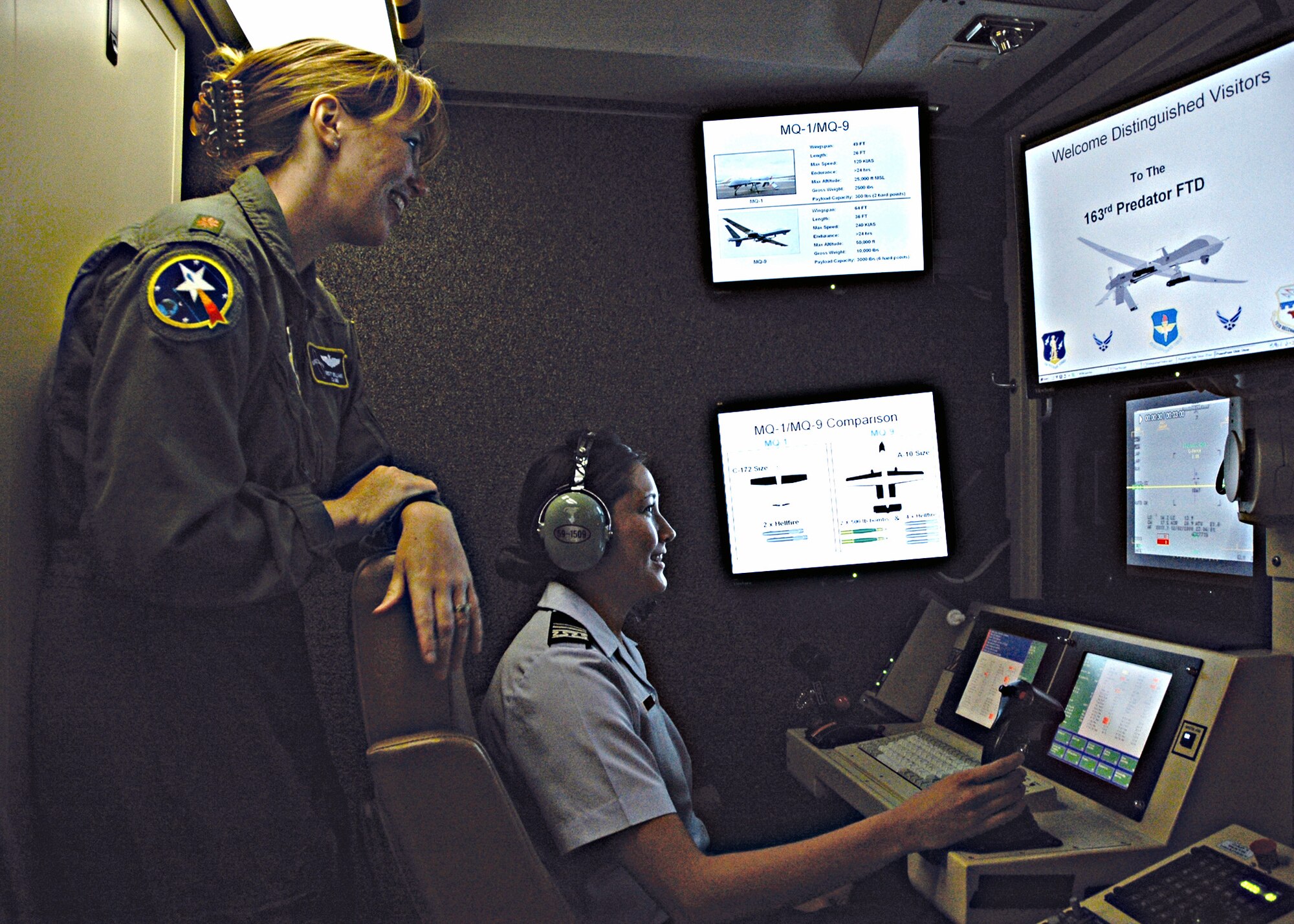 A Predator pilot discusses the 163rd Reconnaissance Wing's UAV operations while U.S. Air Force Academy Cadet 2nd Class Leah Weis sits at the controls inside a Predator Ground Control Station during a tour of 163d RW facilities. During the tour, Cadet Weis also visited the 452nd Air Mobility Wing where she toured a C-17 and acted as the co-pilot in a KC-135 simulator. (U.S. Air Force photo by Capt Al Bosco/163d RW)