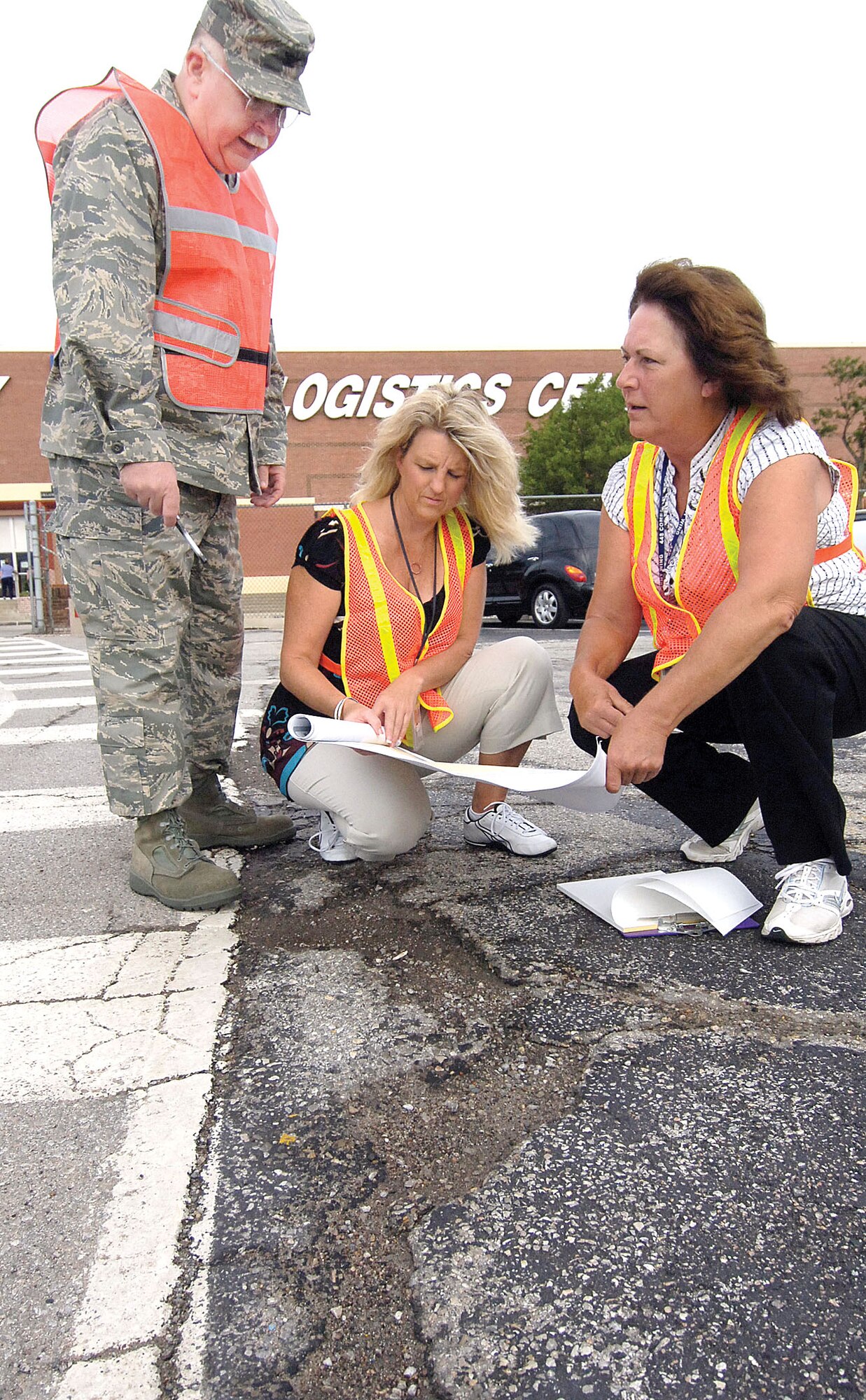 Donning orange reflector vests, a team from the Voluntary Protection Program Combind Wing Staff Group, assess the damage in the parking lot of Bldg. 3001. From left, Col. William Simpson, Susan Ledford and Susan Arnett. 