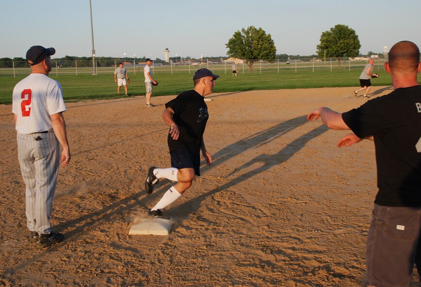 932nd Airlift Wing commander Col. Jay Flournoy runs around third base and keeps an eye on the defense as they chased a ball hit by "DJ" Ellis.  Coach Box at third gave the "caution" sign as the ball came back toward home plate.  Photo/Maj. Stan Paregien
