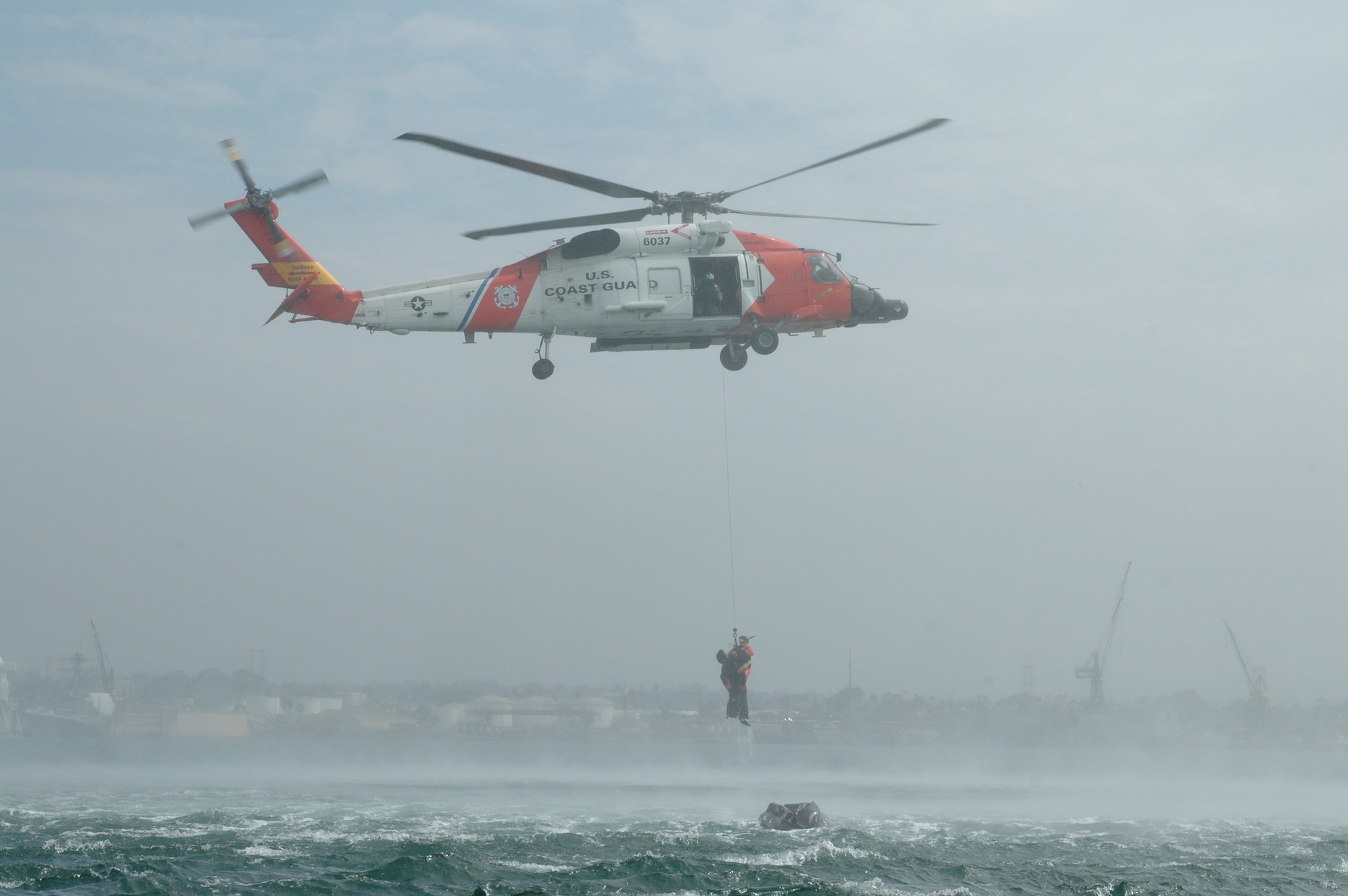 An MH-60J Coast Guard helicopter piloted by Lt. Jeremy Denning and Lt. John Filipowicz maneuvers so rescue swimmer AST3 Logan Banner can extract Dr. (Lt. Col.) Tom Rotkis from the ocean. Extraction was one part of the water survival training conducted during the July unit training assembly at Naval Amphibious Base Coronado in San Diego. “It’s disorienting out there, and the rotor wash is amazing,” said Dr. Rotkis, a flight surgeon at the 162nd Fighter Wing. (Air National Guard photo by 1st Lt. Dan Dodson)