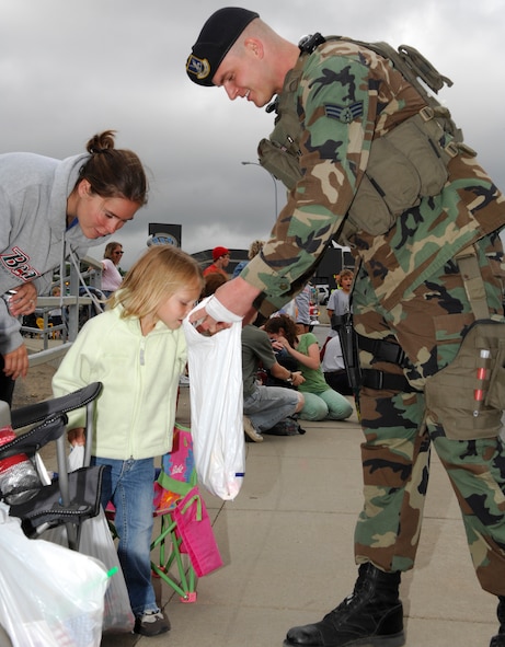 MINOT, N.D. – Senior Airman Vincent Tentis, 791st Missile Security Forces Squadron response force leader, hands out candy to Peyton Skoglund, daughter of David Skoglund, 5th Civil Engineer Squadron electrical engineer, while she enjoys the North Dakota State Fair Parade here July 20. Both the 5th Bomb Wing and 91st Missile Wing were well represented during the parade. (U.S. Air Force photo by Staff Sgt. Thomas Dow)