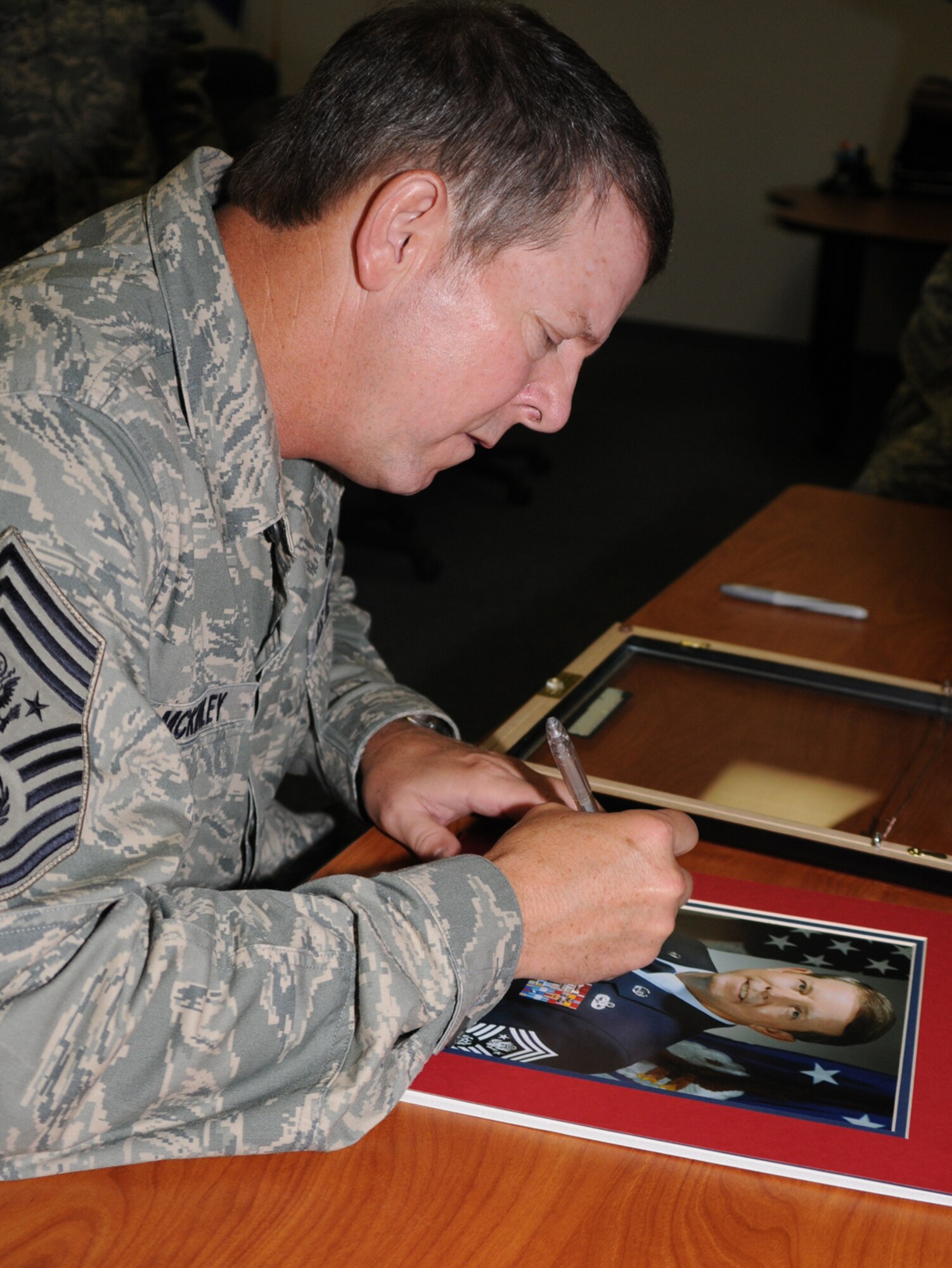 Chief McKinley signs his photograph to be displayed at Airman Leadership School along with pictures of the other 14 chiefs to hold the Air Force’s top enlisted position.  (U.S. Air Force photo by Kemberly Groue)